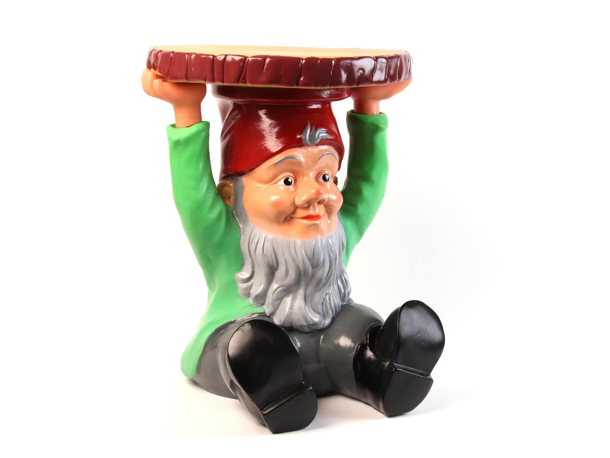 Garden gnome figure with red pointed hat, green shirt, and black boots holding up circular brown wooden surface as table top.