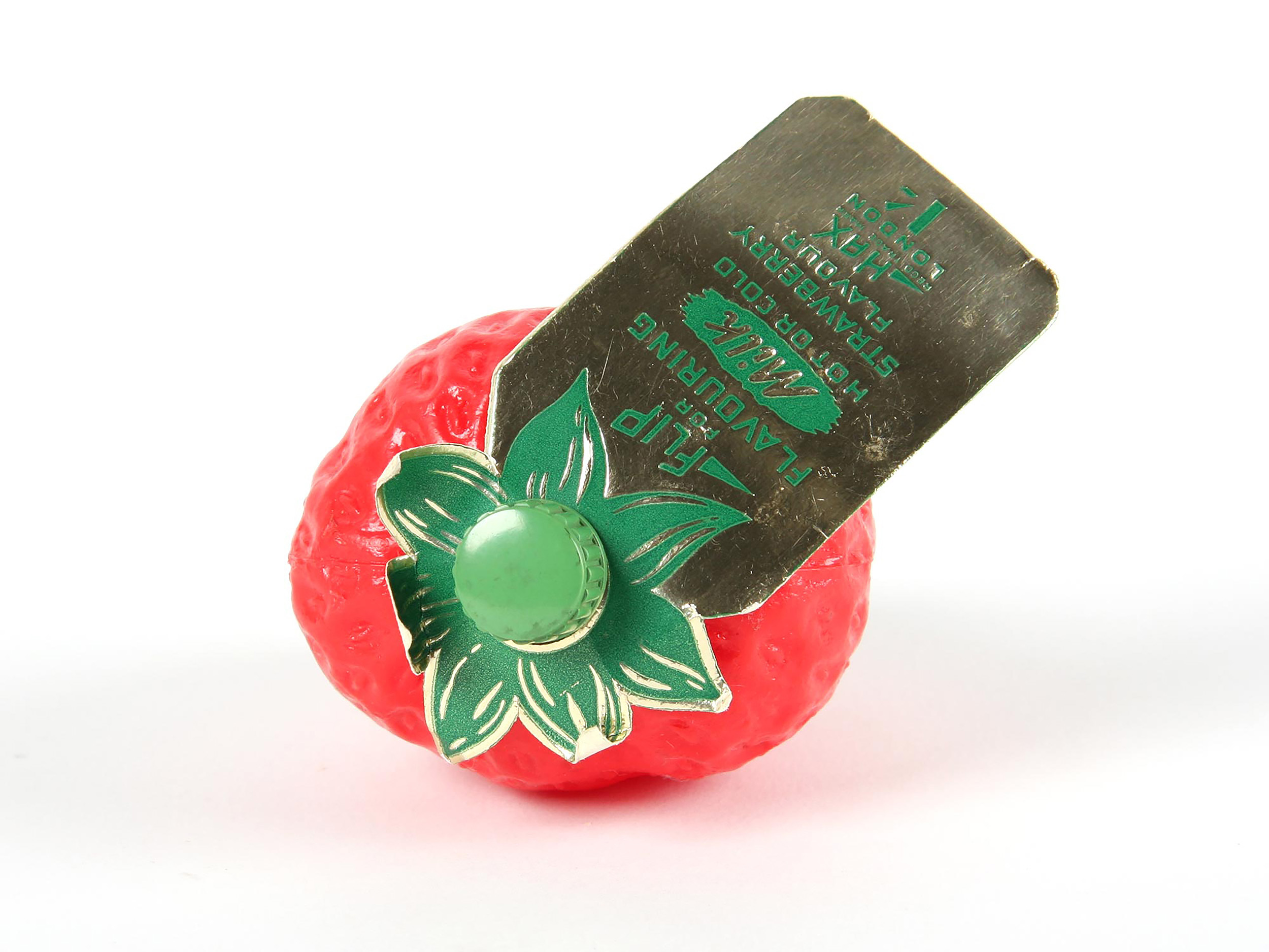 A plastic strawberry with a lid made out of the stalk. A label is attached to the lid.