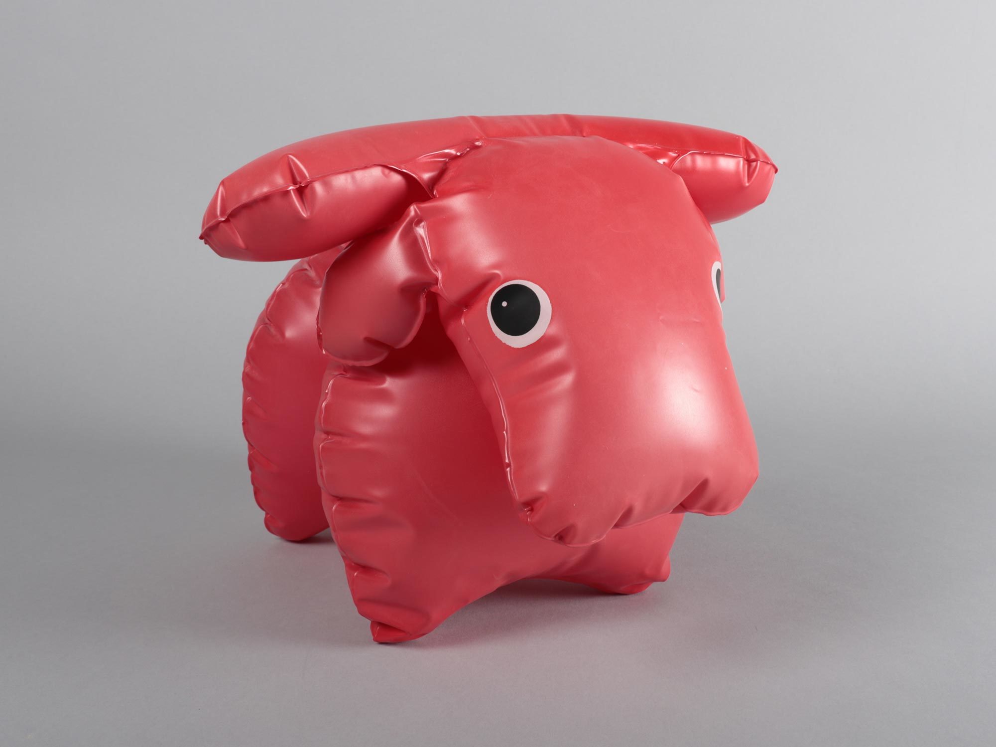 Red inflatable toy of a buffalo calf with big eyes.
