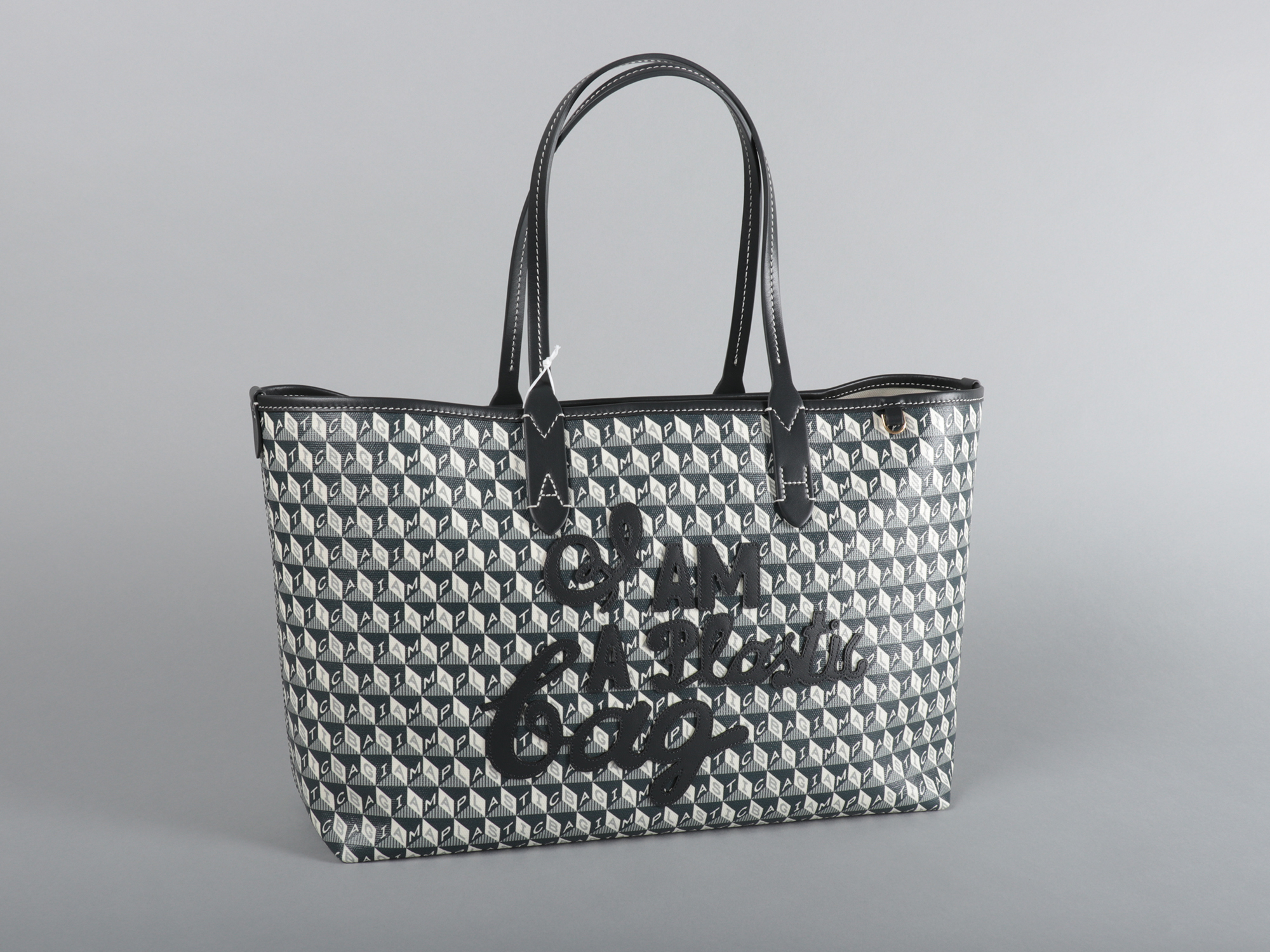Plastic handbag with a black cube design with the words "I AM A PLASTIC BACK" spelled out across the bag. The words "I AM A PLASTIC BAG" are also stitched in assorted fonts on the body of the bag.