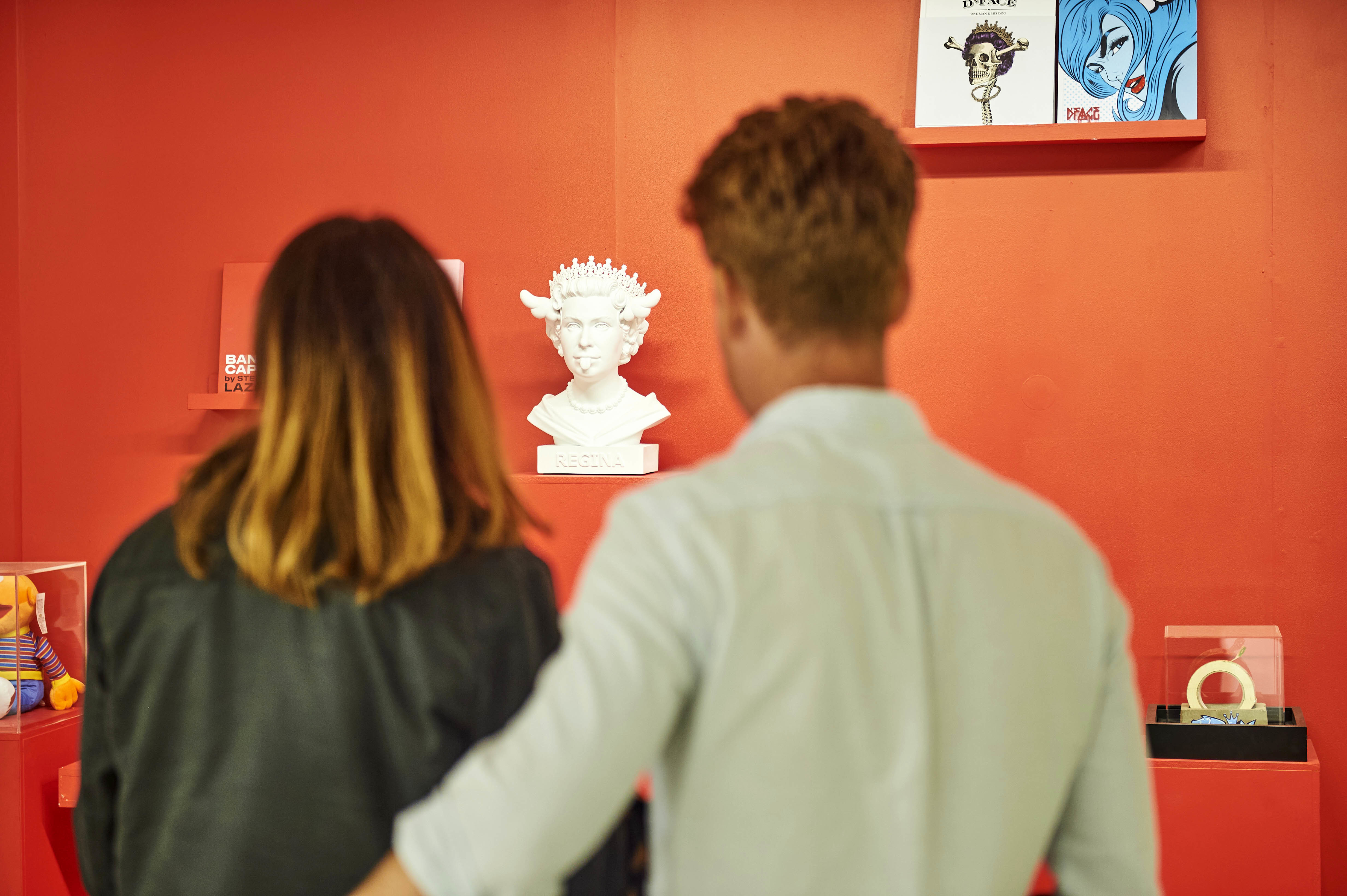Two people with their backs to the camera looking at exhibits at a gallery show.