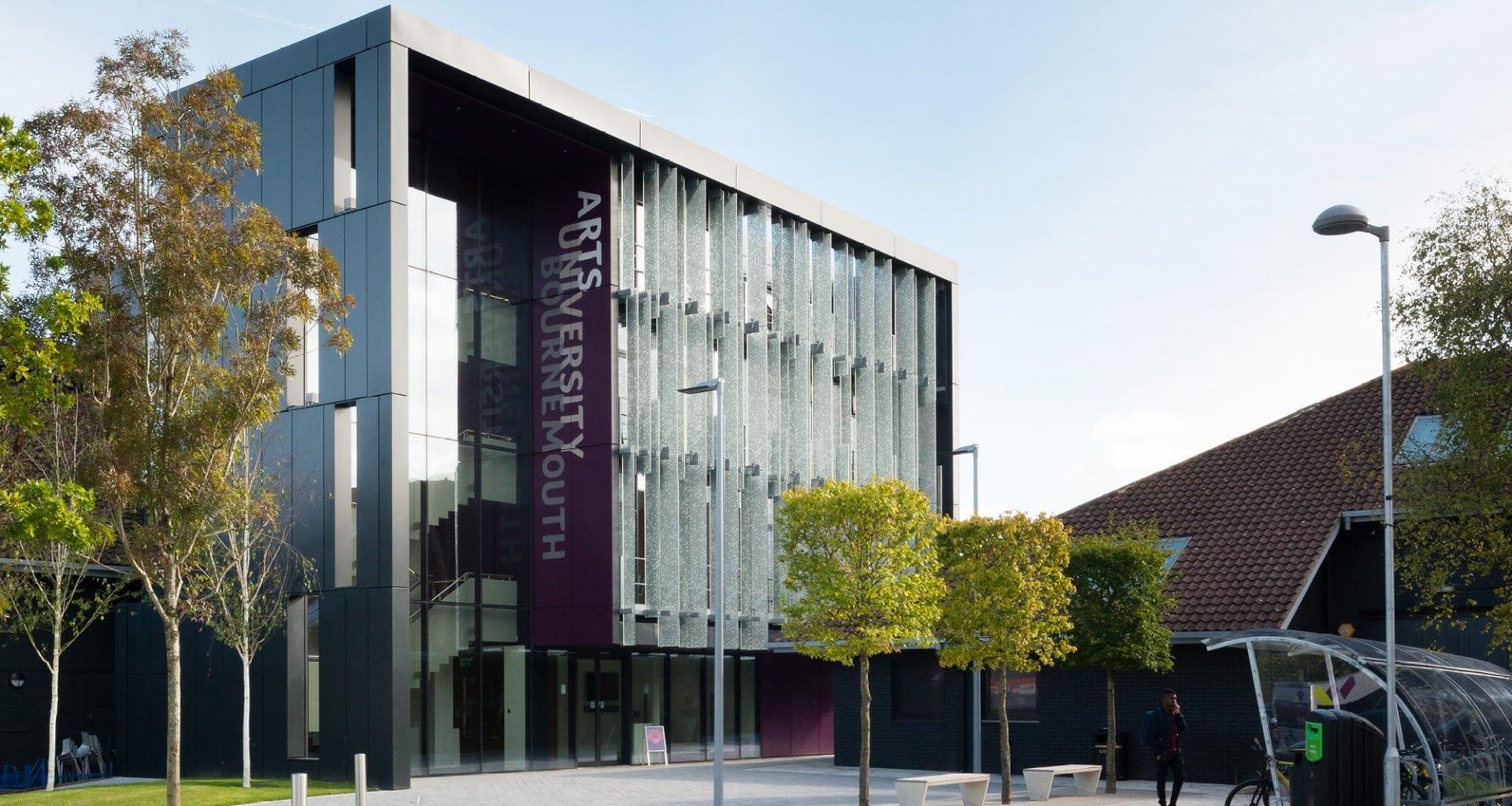 Large university building with Arts University Bournemouth written down the side. In front are square-shaped trees.