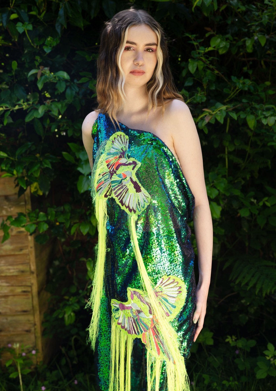 Model wearing an embroidered green sequin dress outside.