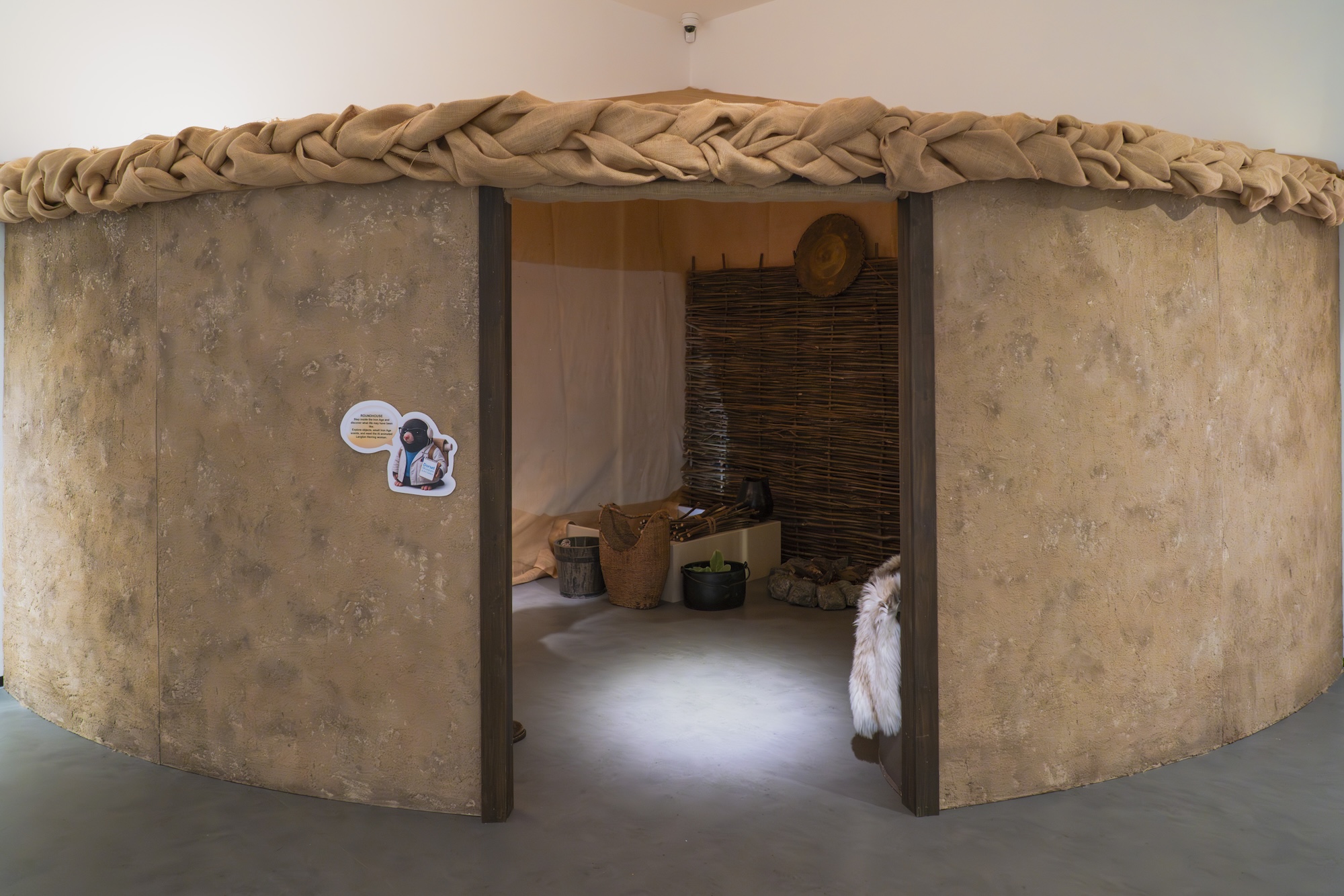 A round canvas hut or tent-like structure with a wide entrance and wickerwork structures inside it.
