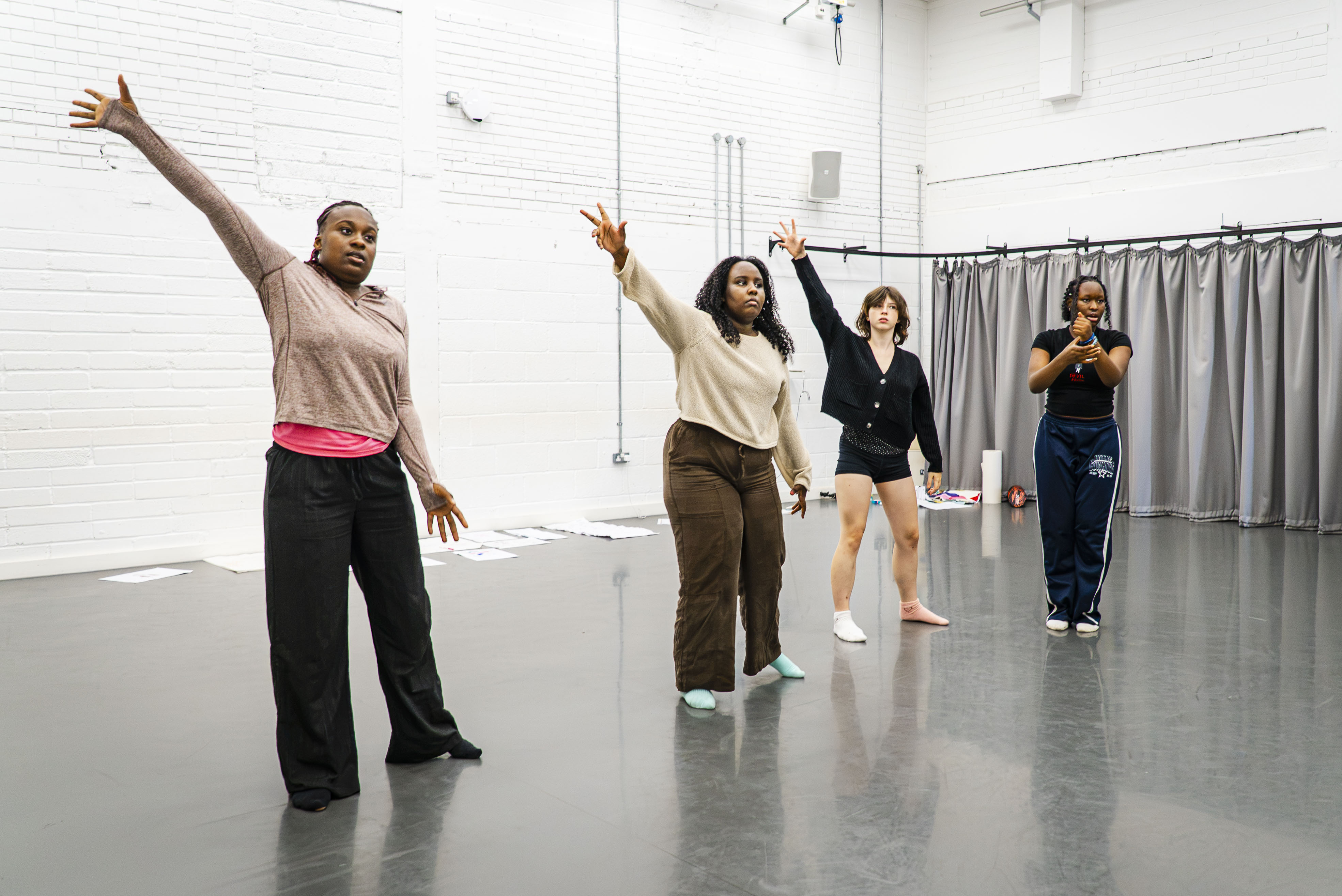 Four young people posing as part of a dance routine in a dance studio.