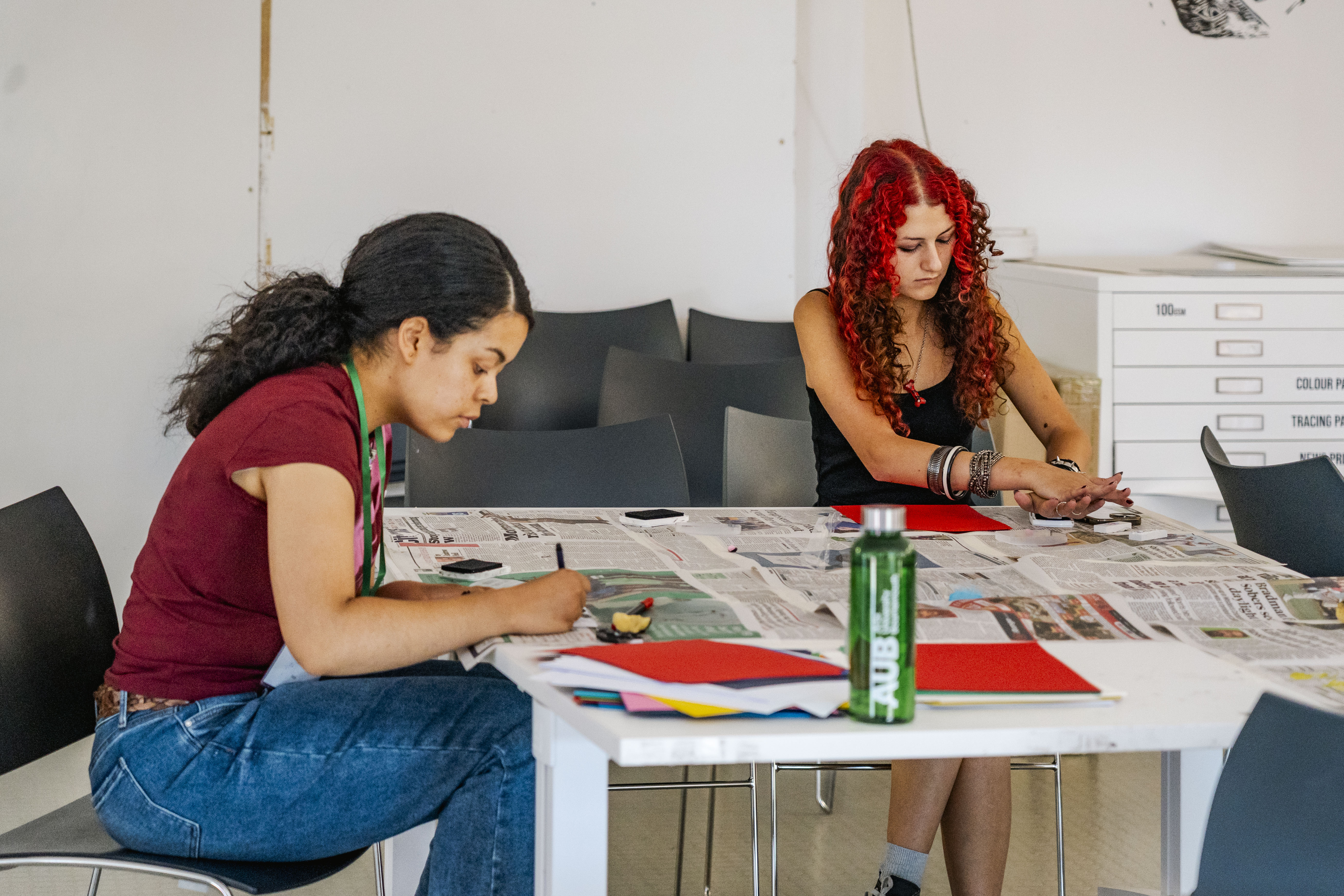two students sat at desk focused on creating their art work