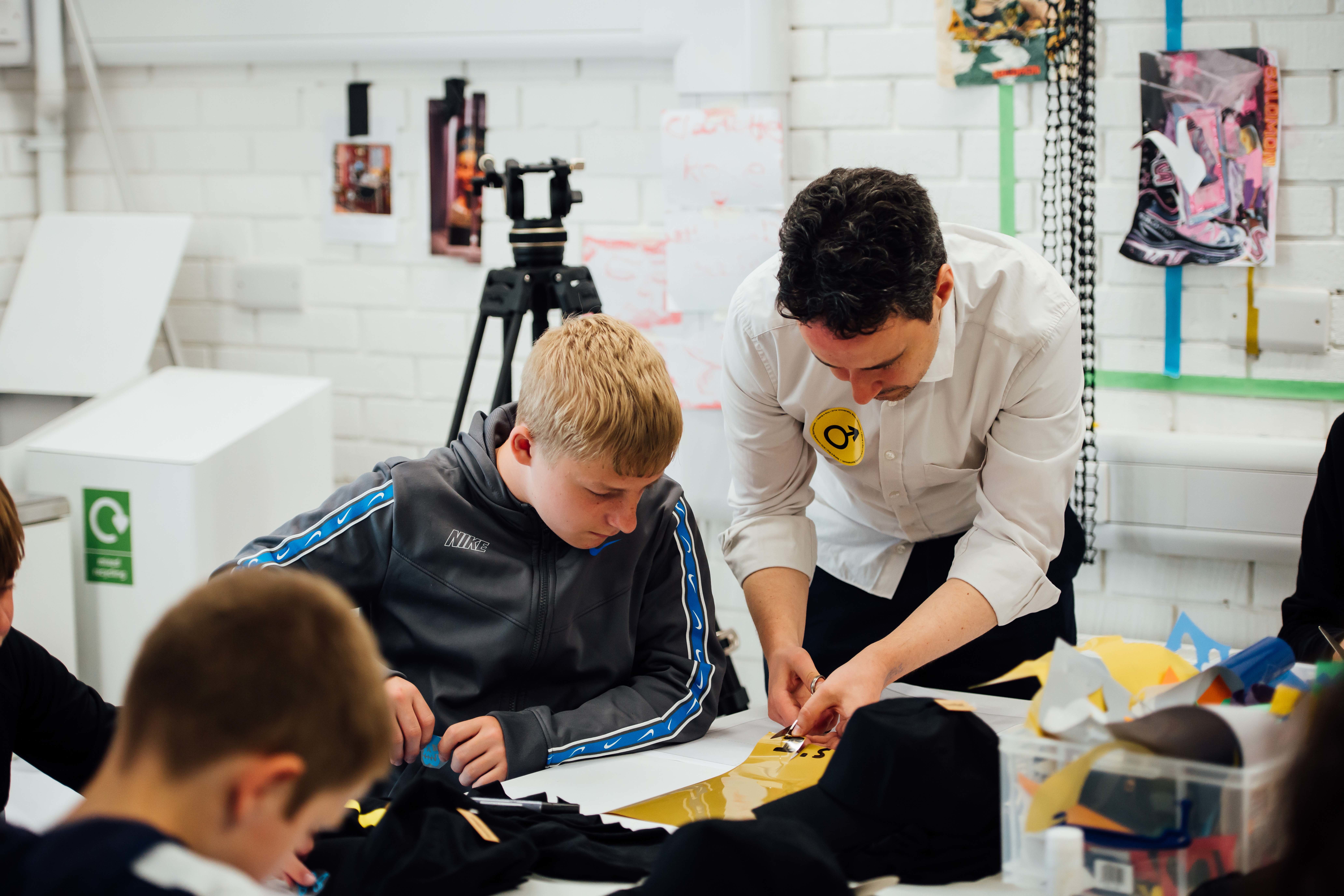 Tutor assisting two boys in a studio.