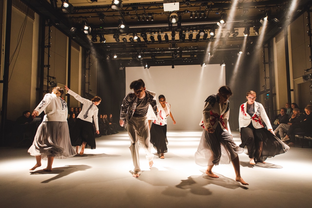 Dance students performing under dramatic lighting for an Alexander McQueen tribute dance show.