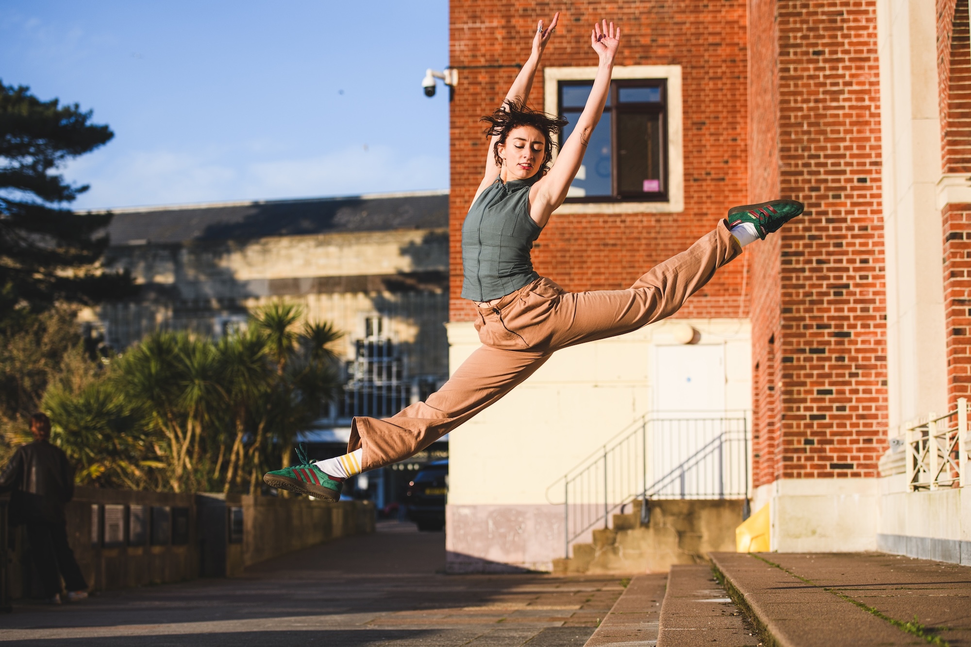 An Arts University Bournemouth student pulls a pose in mid-air, arms raised, having jumped from some steps outside Bournemouth Pavilion.