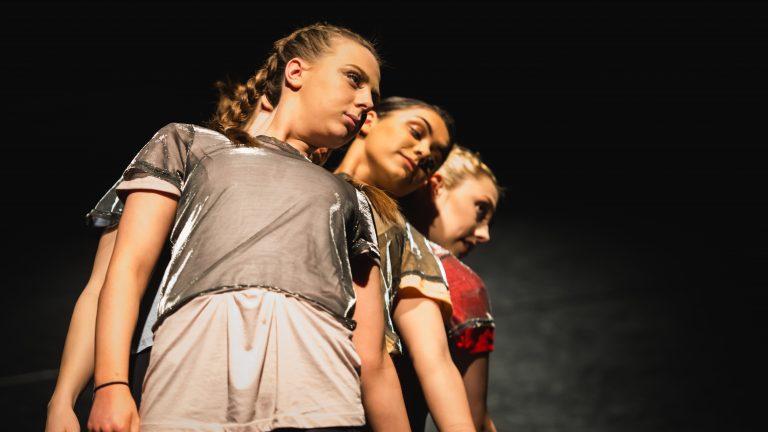 Dance students line up behind one another and lean out
