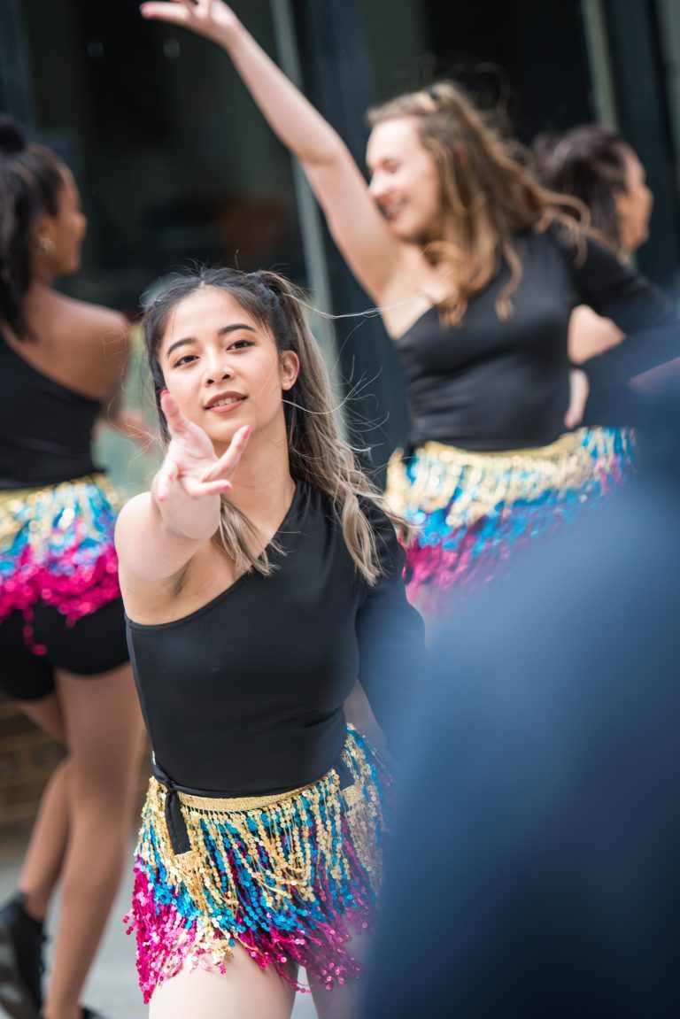 A dancer in costume reaches out towards the camera.