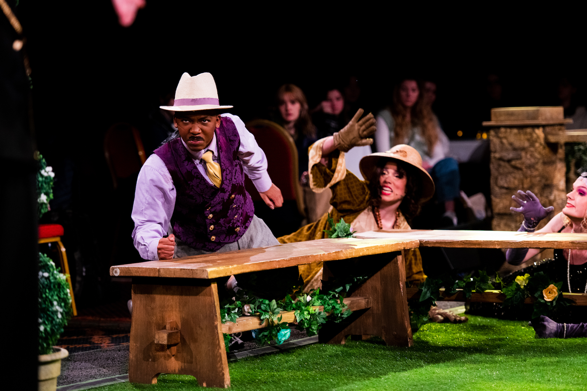 BA (Hons) Acting students performing "Strictly Twelfth Night!" One actor is pounding their fist on a bench while another actor cowers behind them.