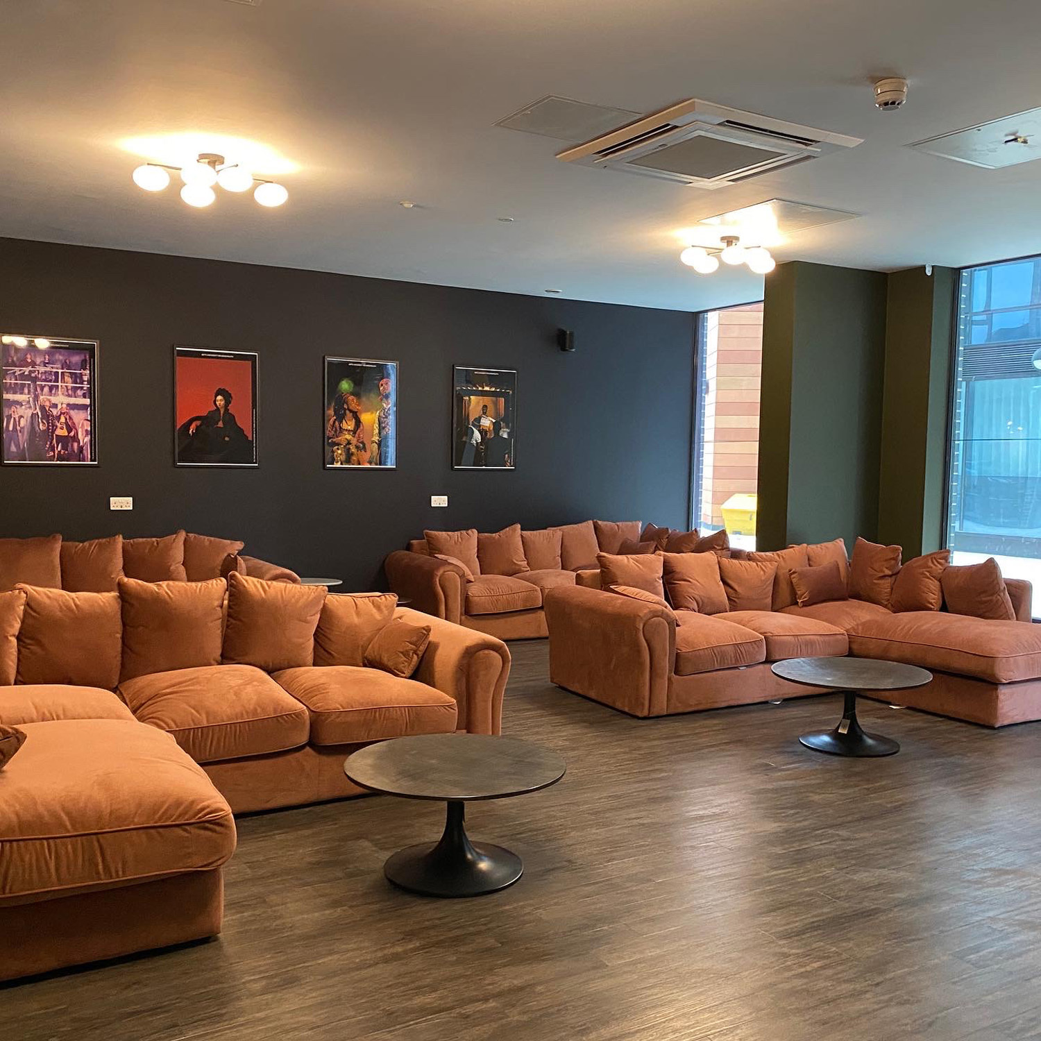A seating area at Home Park, with large, comfy orange sofas and lighting.