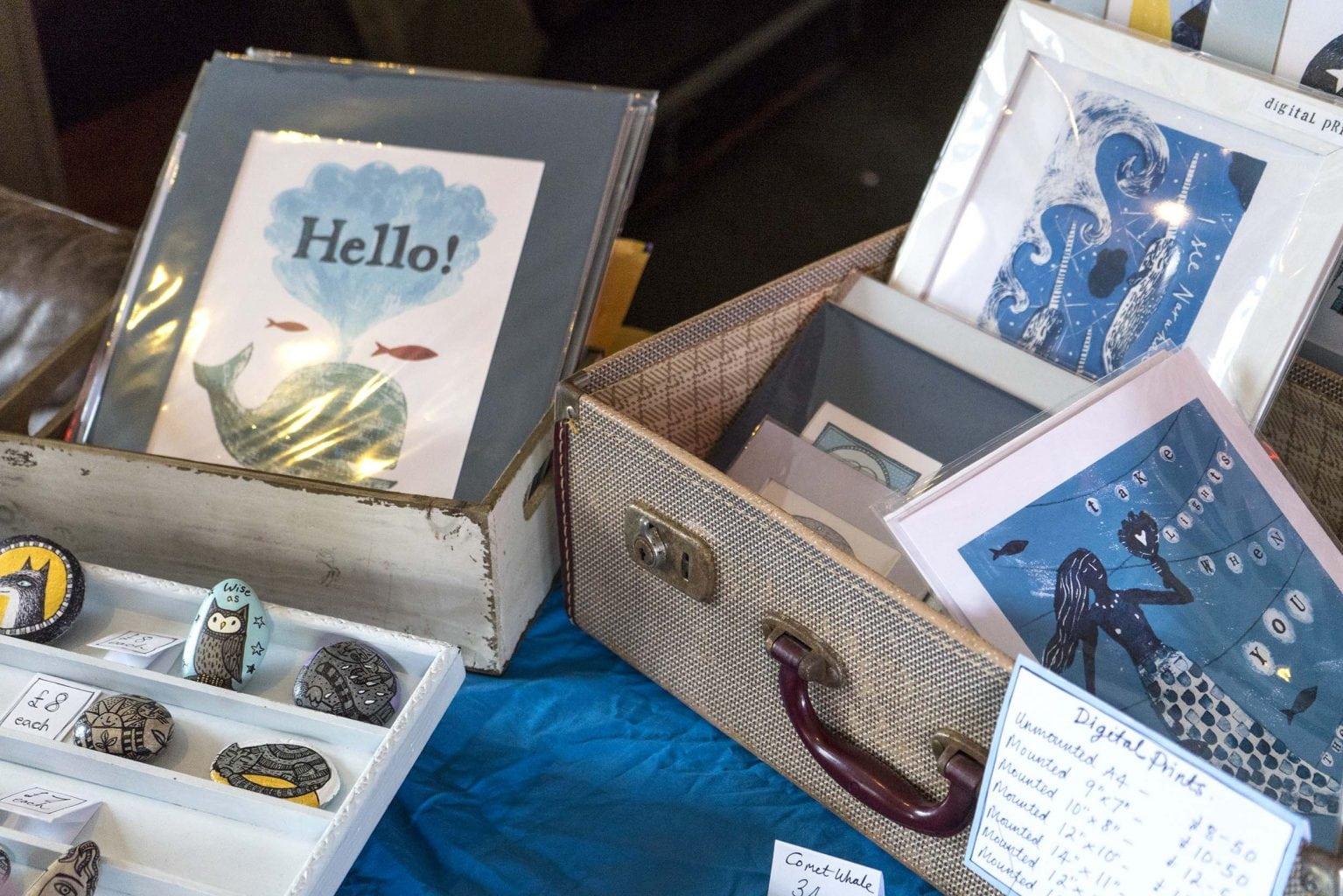 A selection of artwork prints on display in cases on a stall.