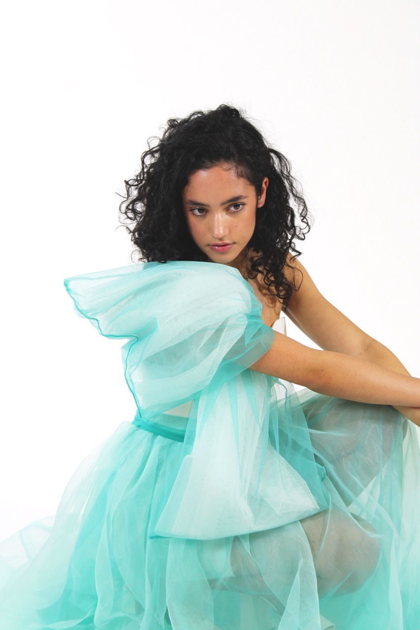 Model wearing a turquoise veil dress, white background.