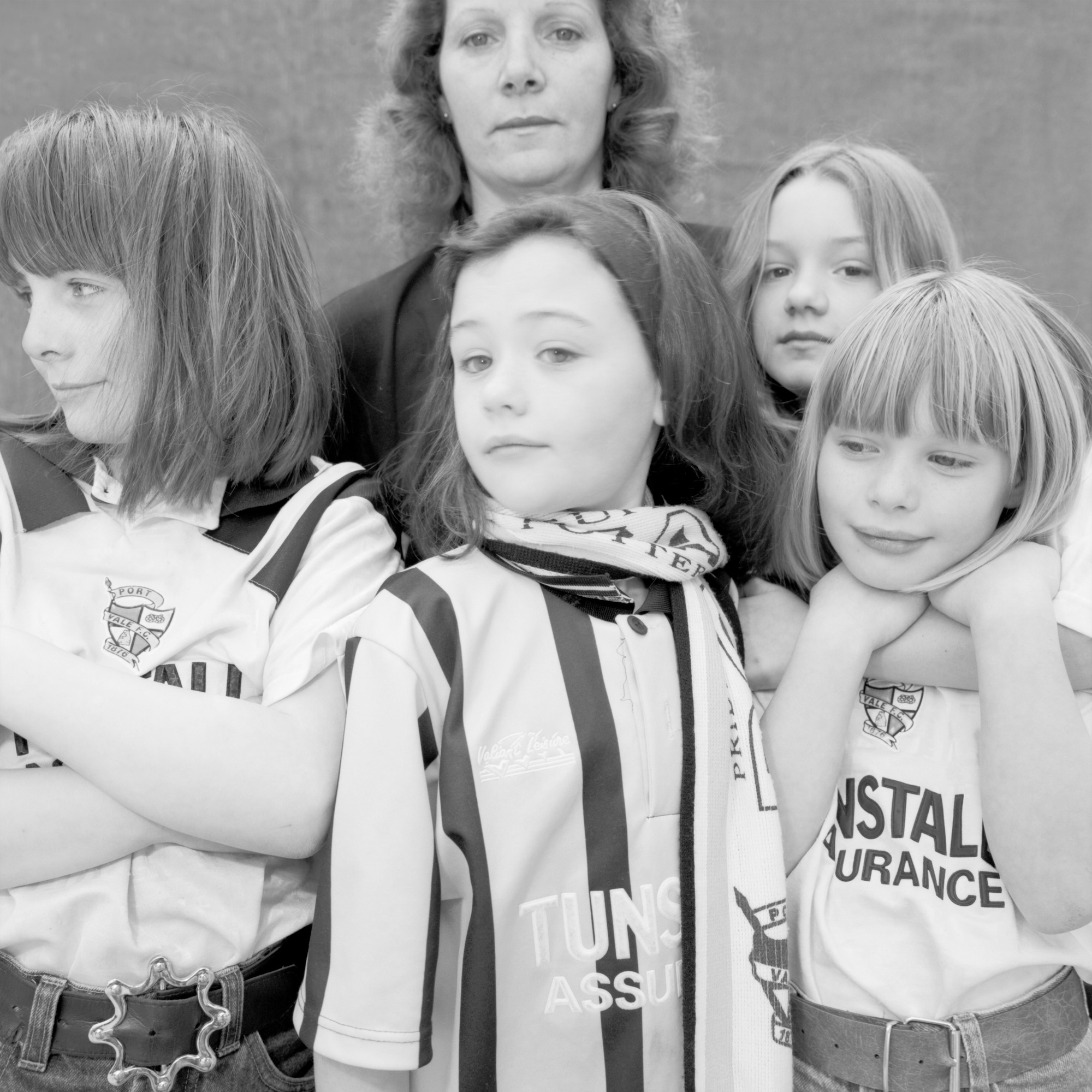 Black and white photo of a mother and four girls wearing football colours.