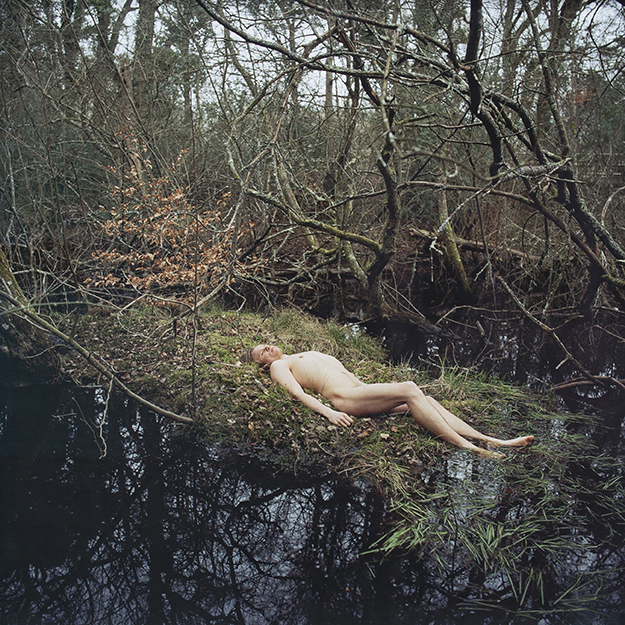 Photograph of naked man lying down in the forest