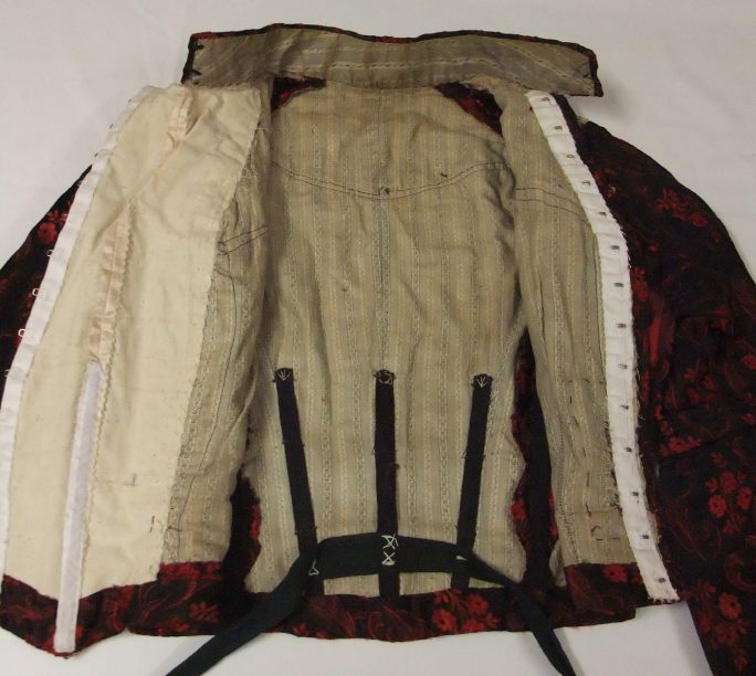 Early 1900s-style silk damask bodice, floral red and black pattern with cream inside, white background.