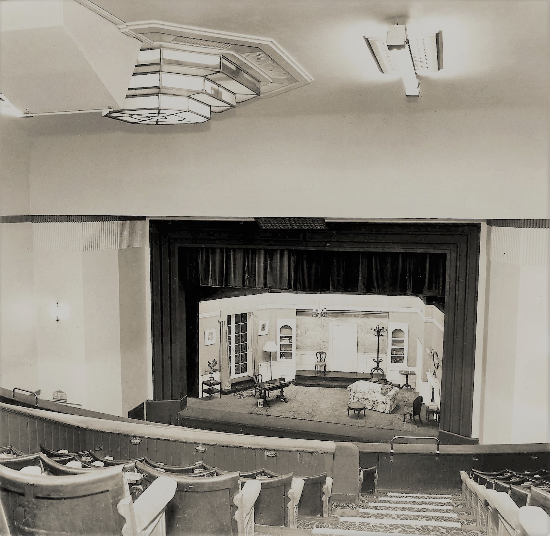 A historic black and white photograph of a 1930s theatre space with a stage set for performance.