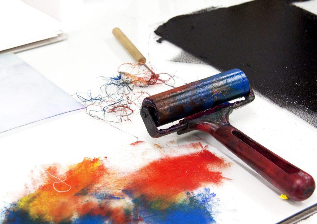 Paint roller on a table, next to an open sketchbook.