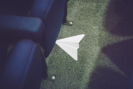 Paper aeroplane underneath a blue sofa