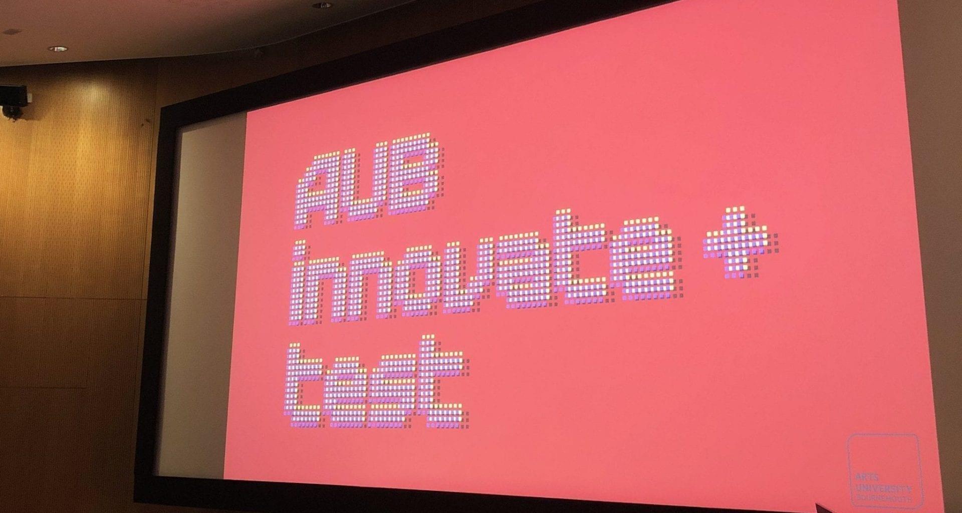 A television screen on a wall shows a graphic that reads 'AUB innovate + test'
