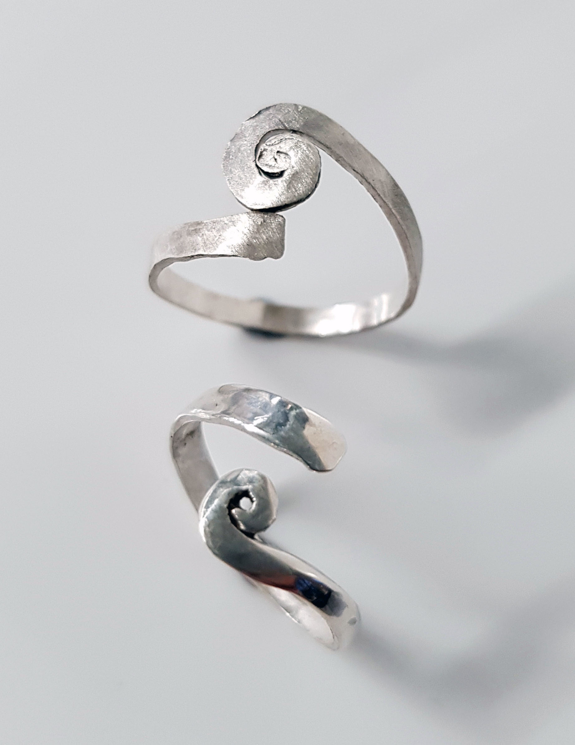 A pair of silver rings with spiral designs.