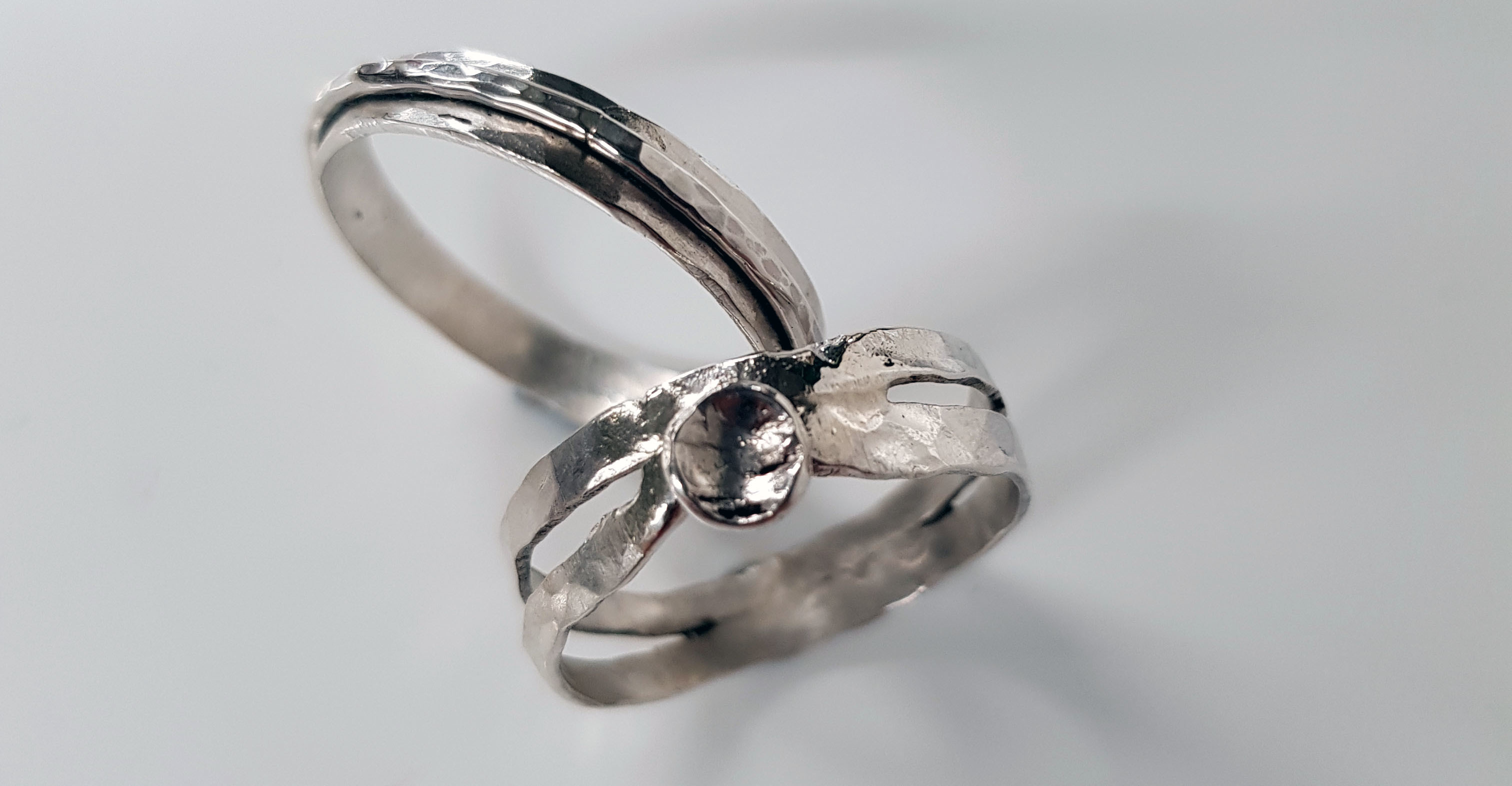 Two silver rings lying next to each other on a plain surface.