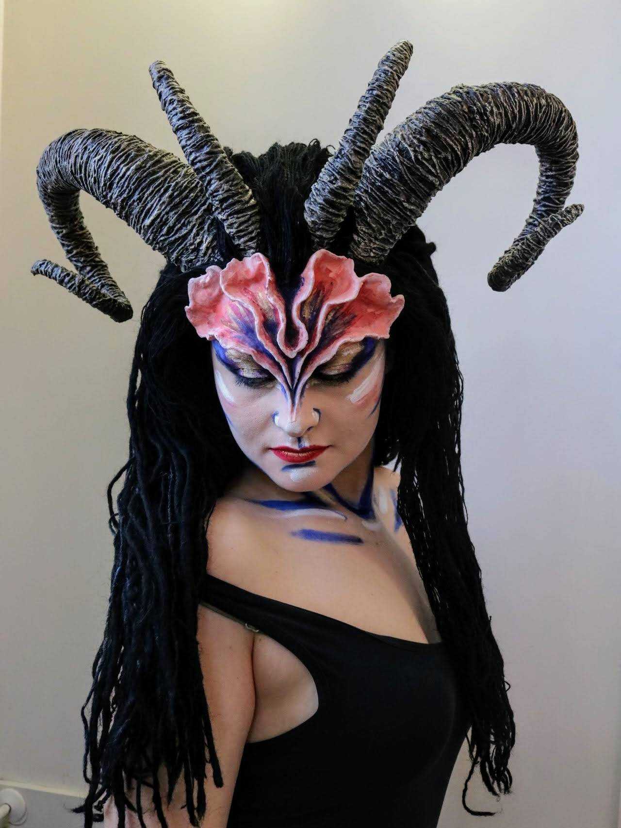 A portrait of a person wearing a horned headdress prosthetic looking down.
