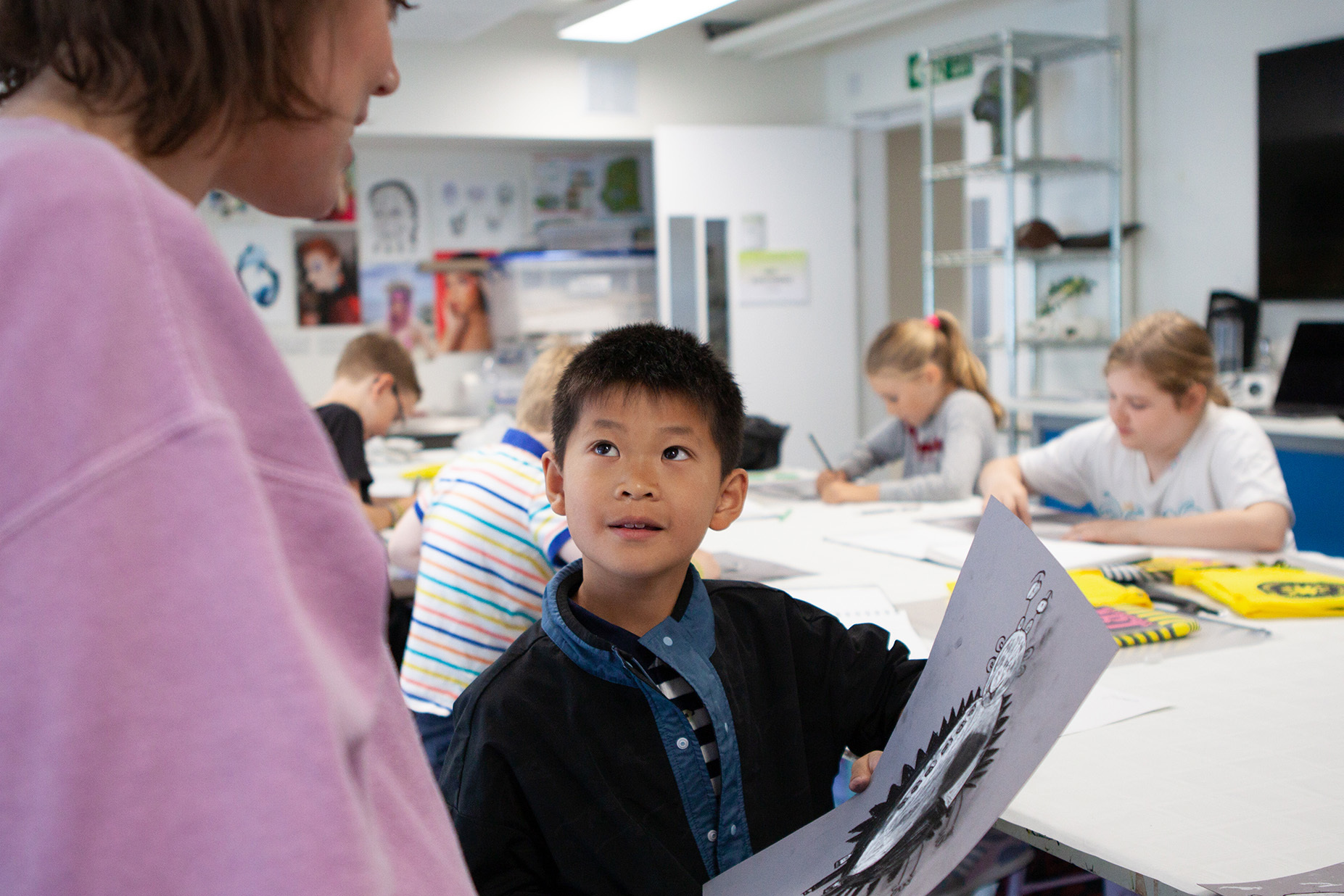 A young student shows their work to a teacher]