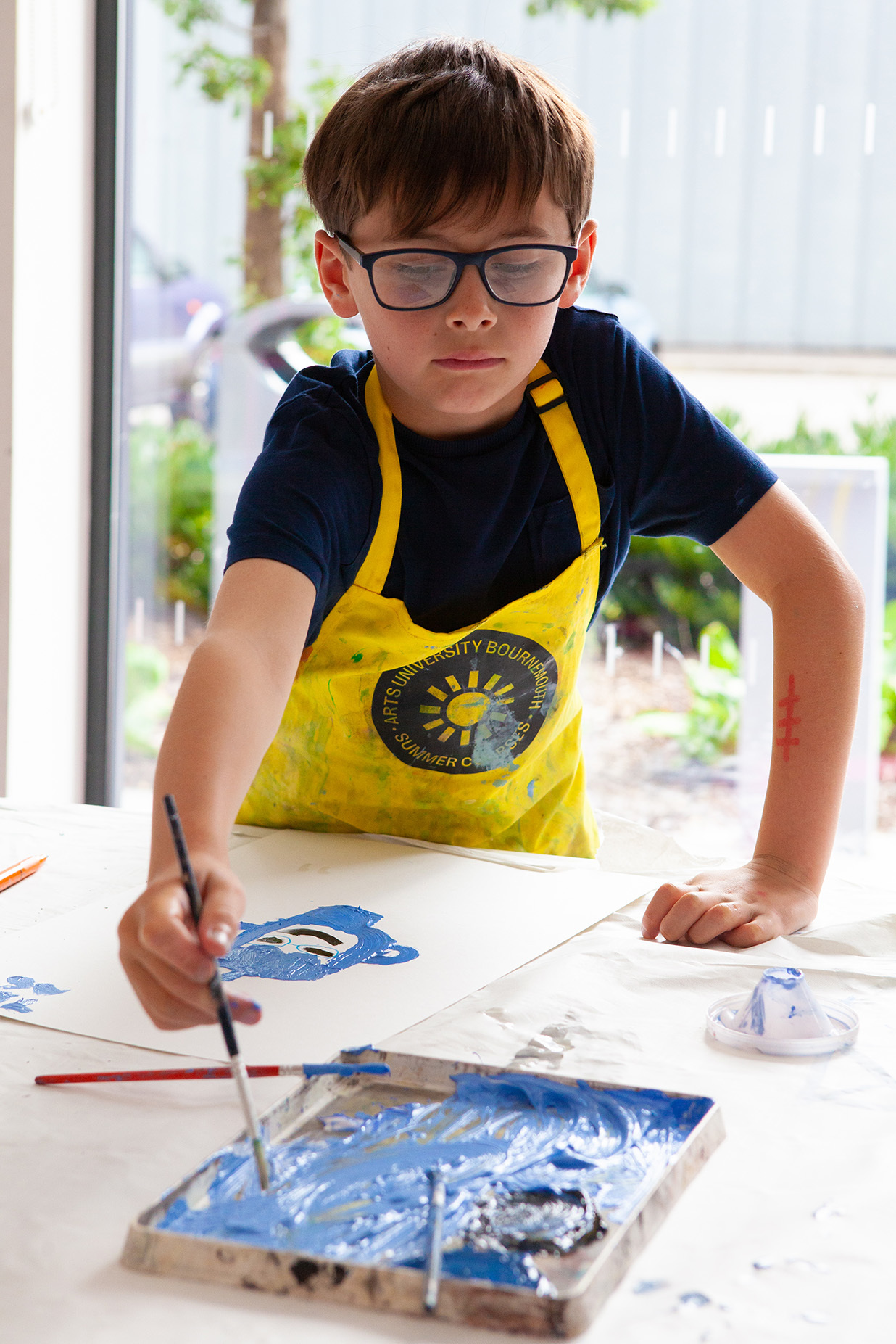 A young student is painting at a table