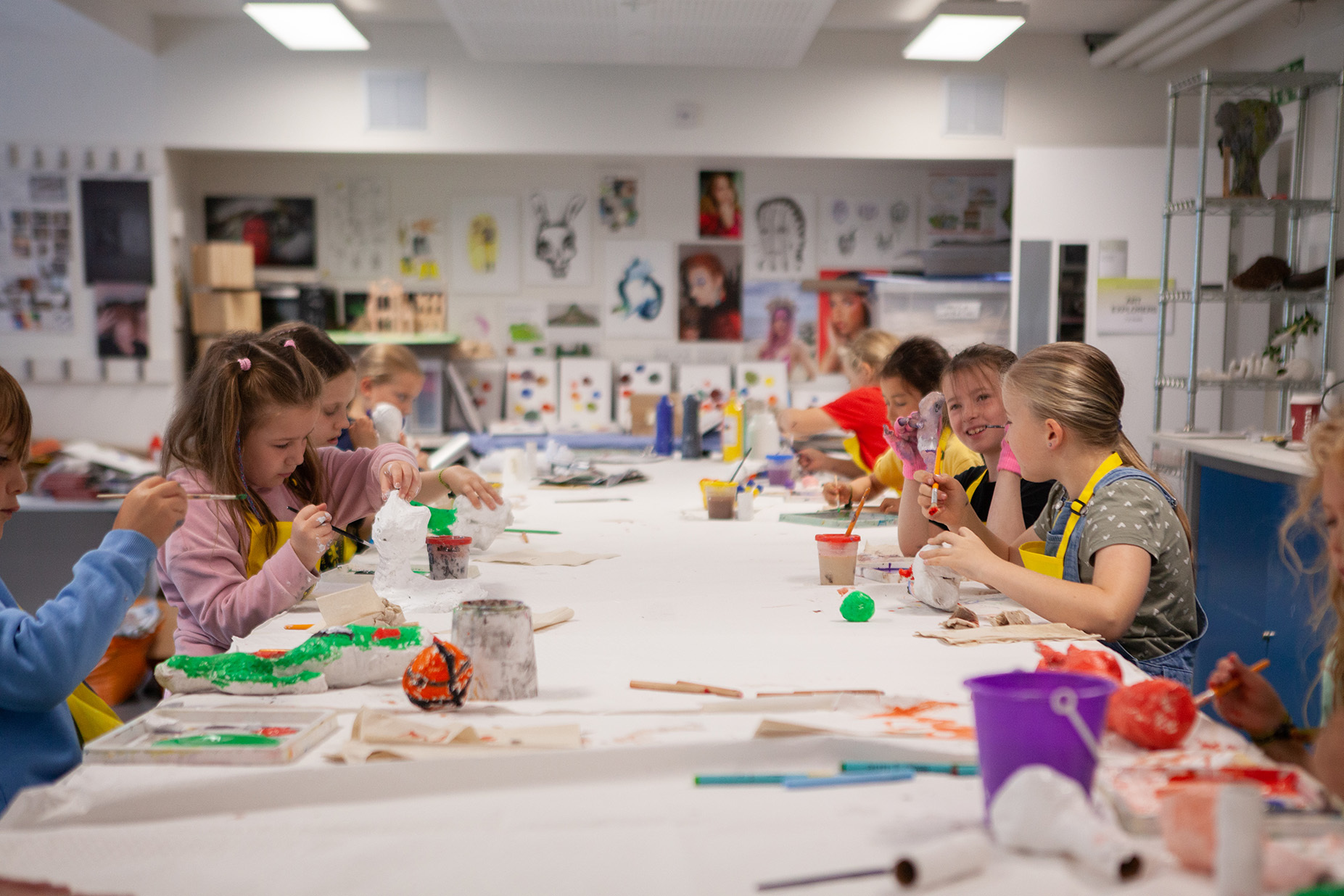 A group of young students are painting around a table