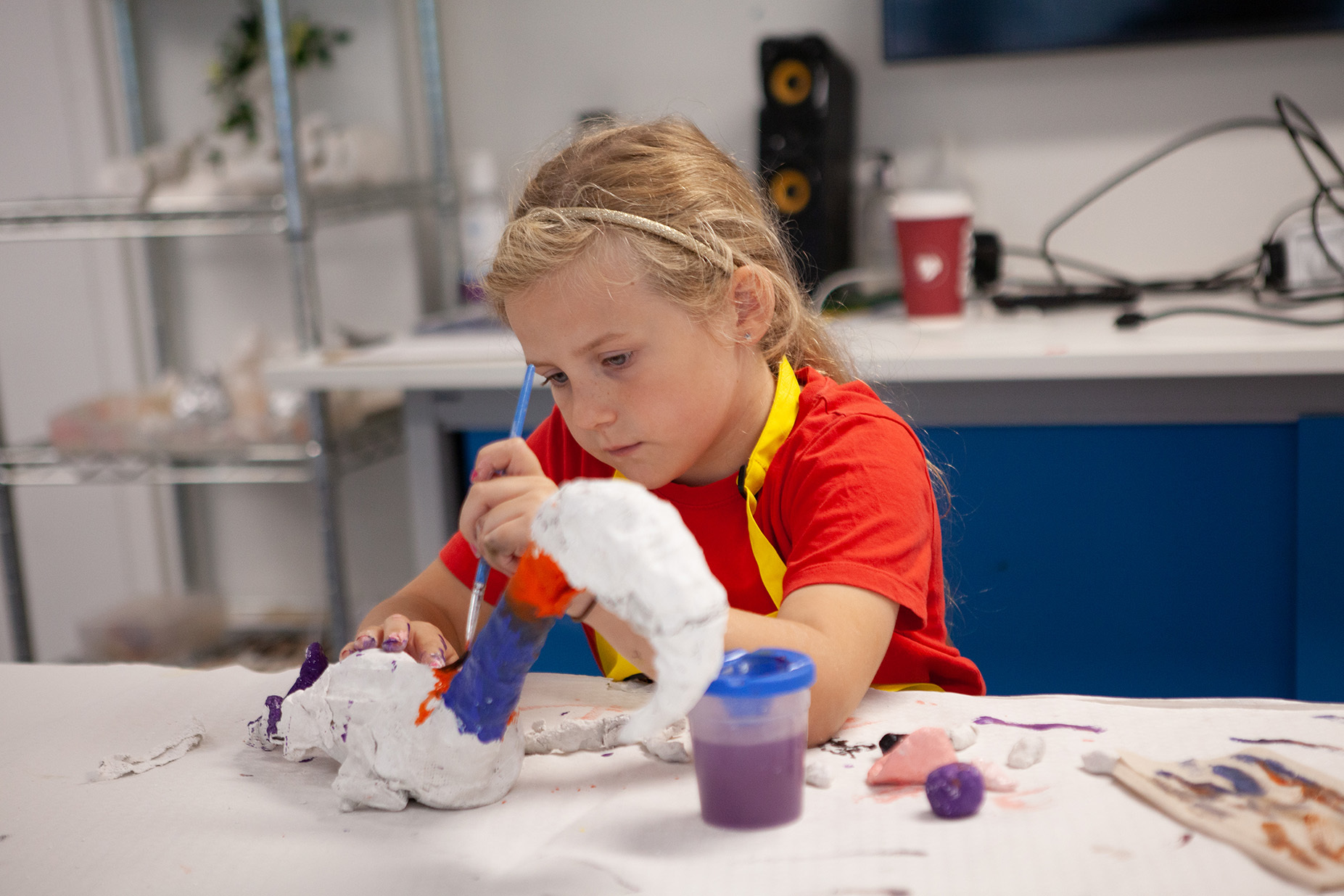 A young student is painting a sculpture