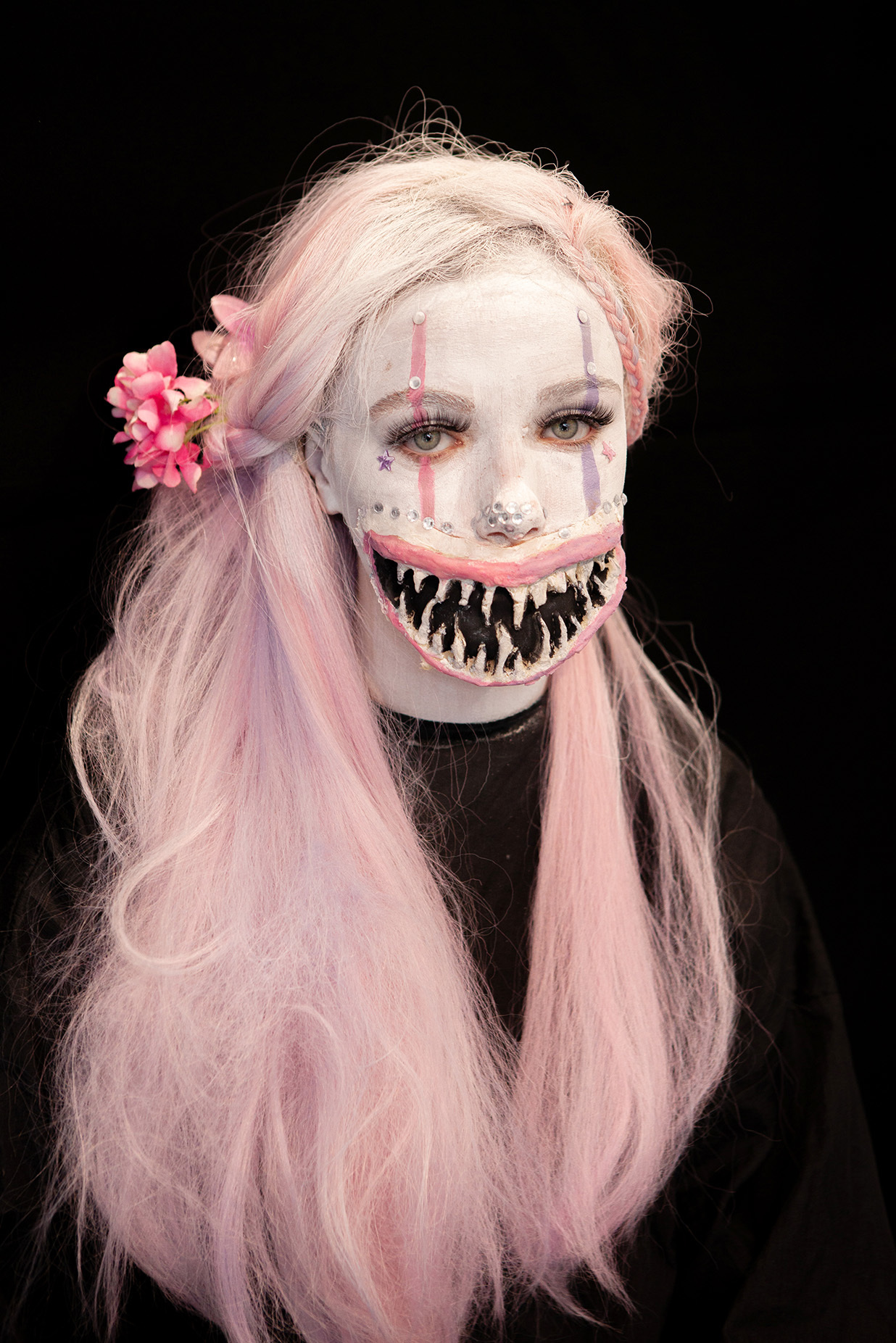 An example of character makeup: student has long pink hair and a large, prosthetic mouth that grins menacingly