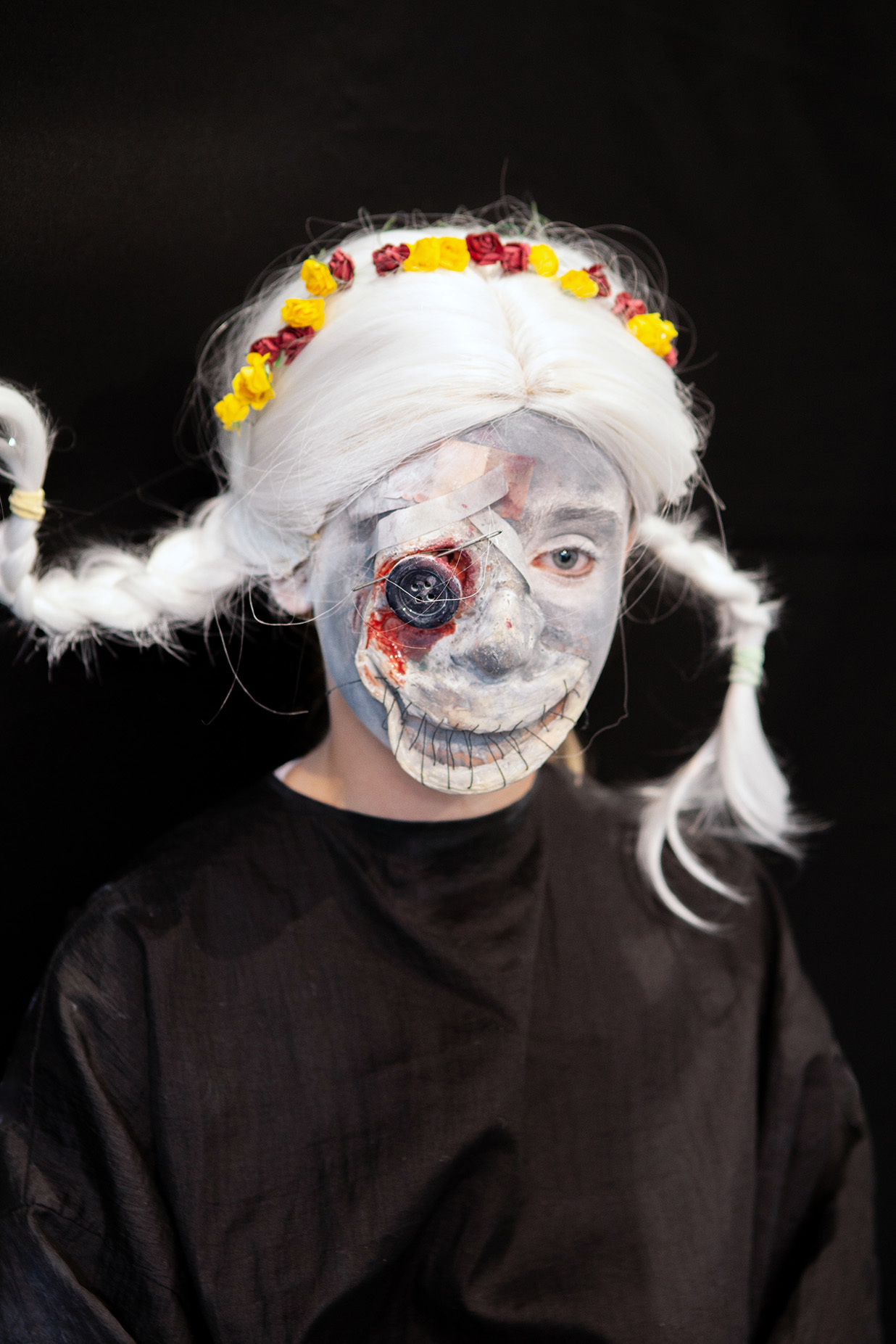 An example of character makeup: a student has their hair in pigtails and has a button prosthetic over an eye socket