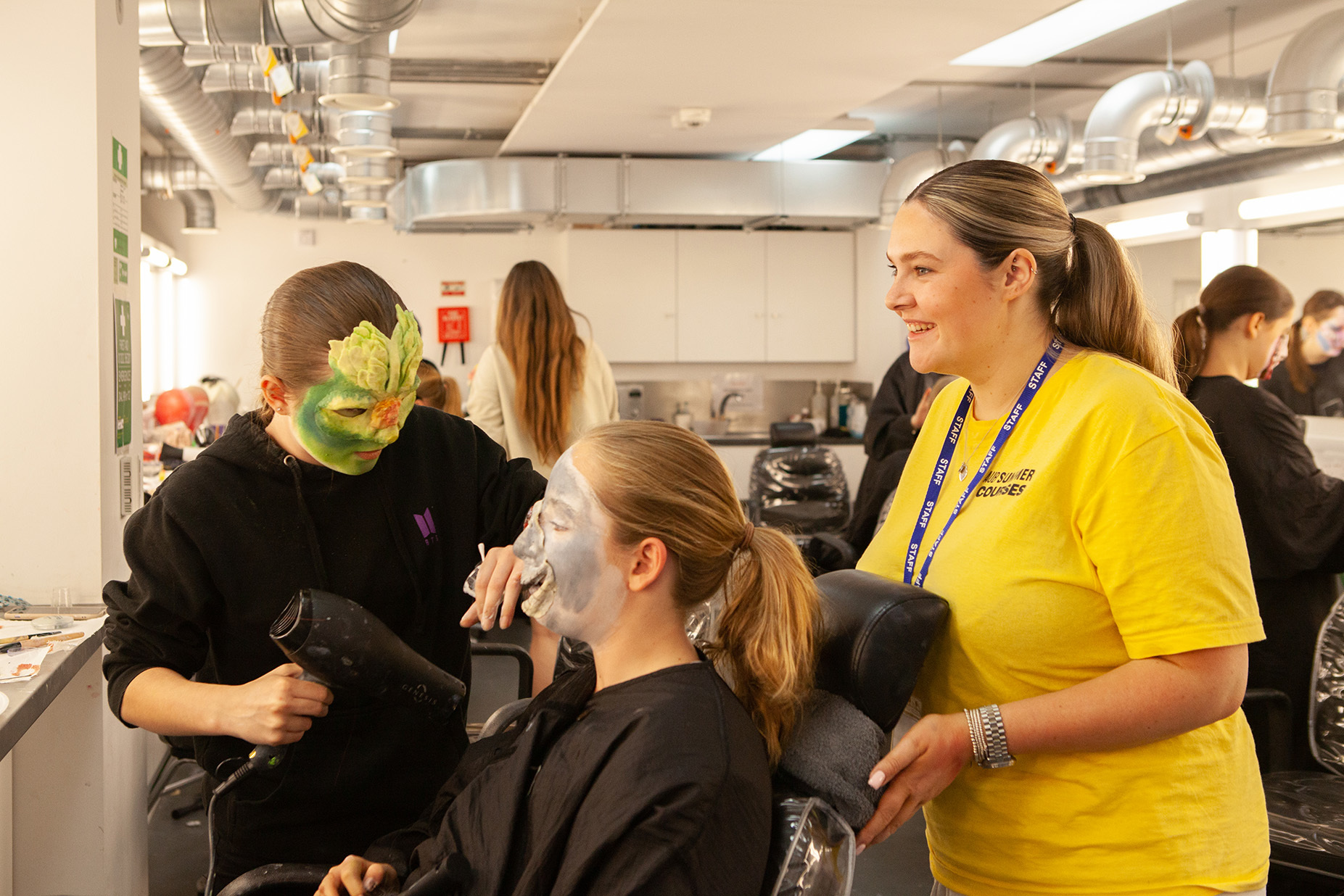 A student is applying makeup to another student's face