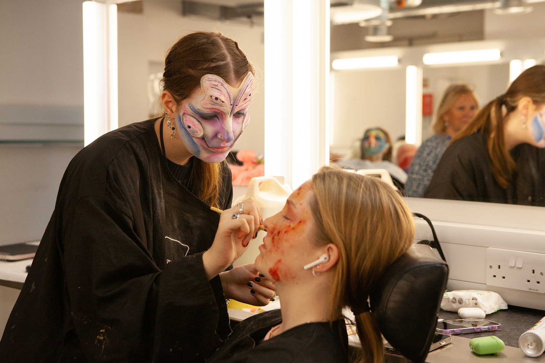 A student is applying makeup to another student's face