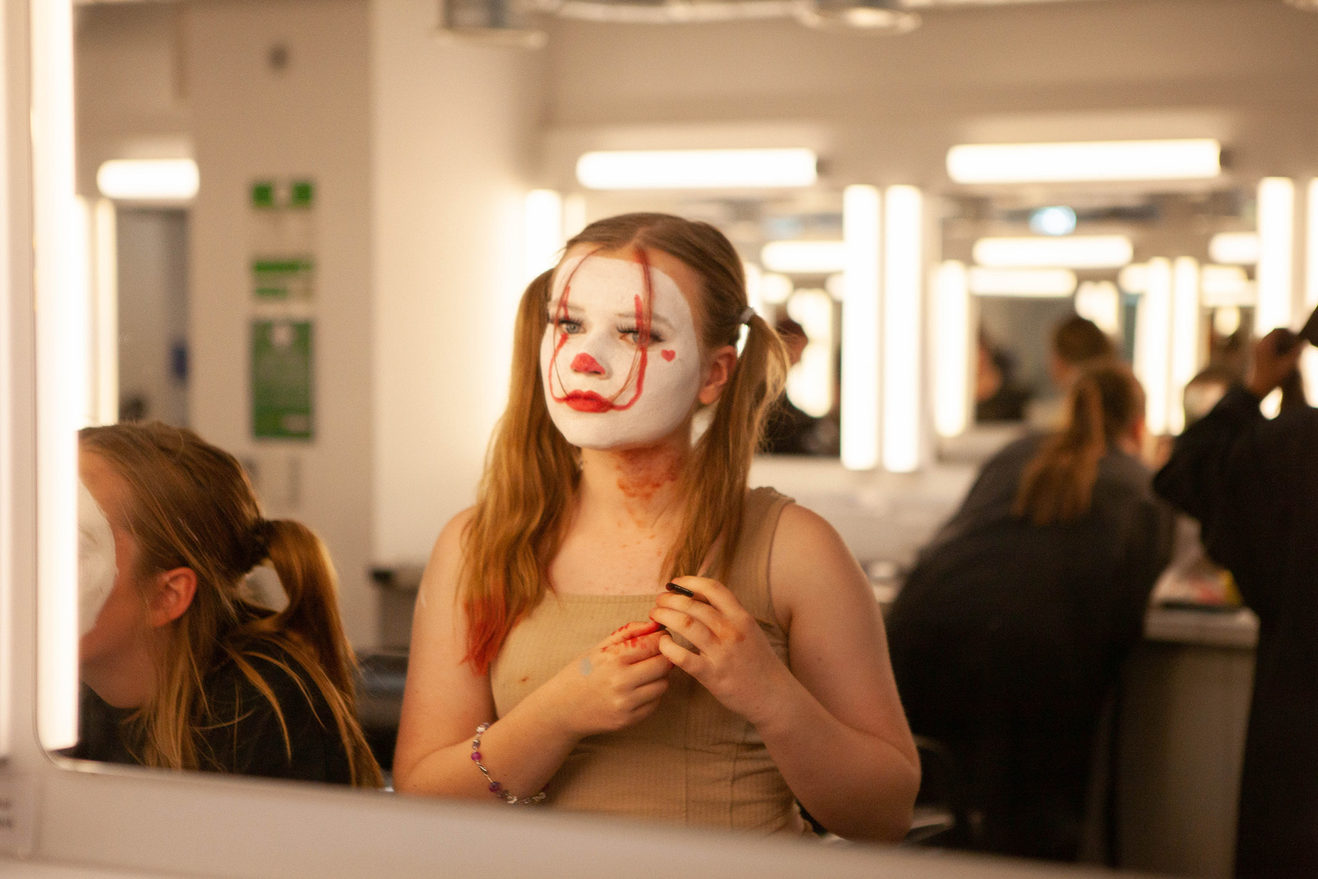 A student is applying makeup to themselves using a mirror