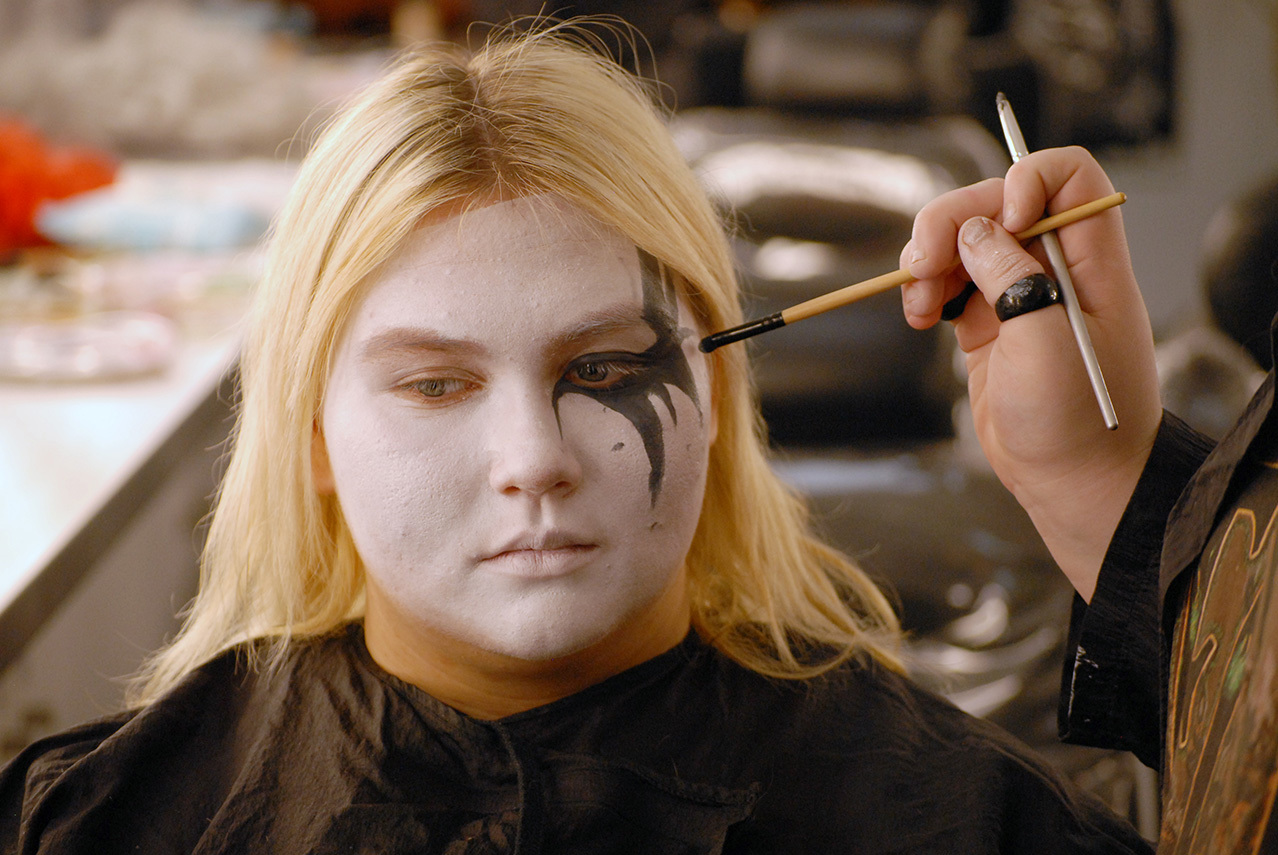A student is applying makeup to another student's face