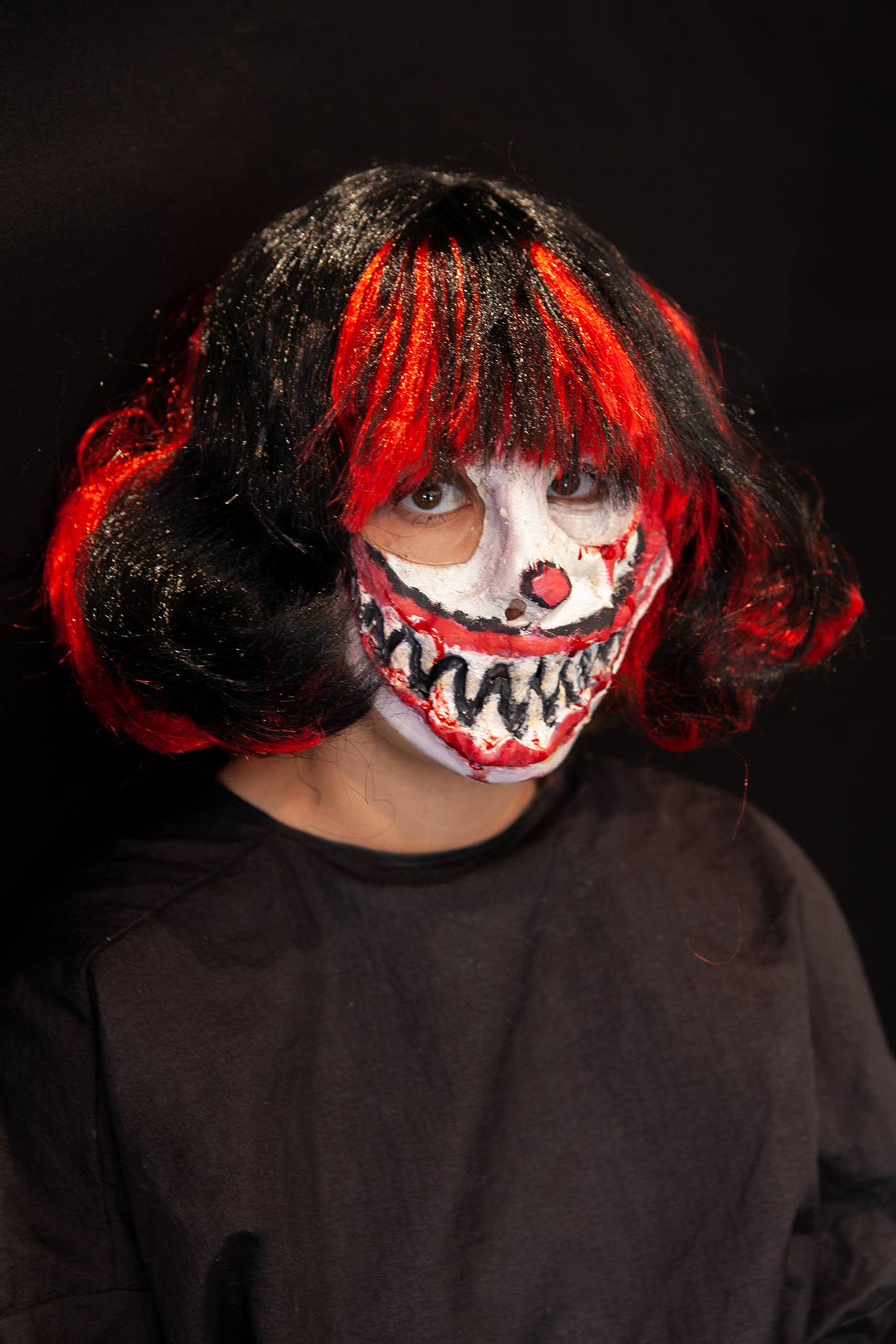 An example of character makeup: student has a black and red striped wig on with a large prosthetic mouth