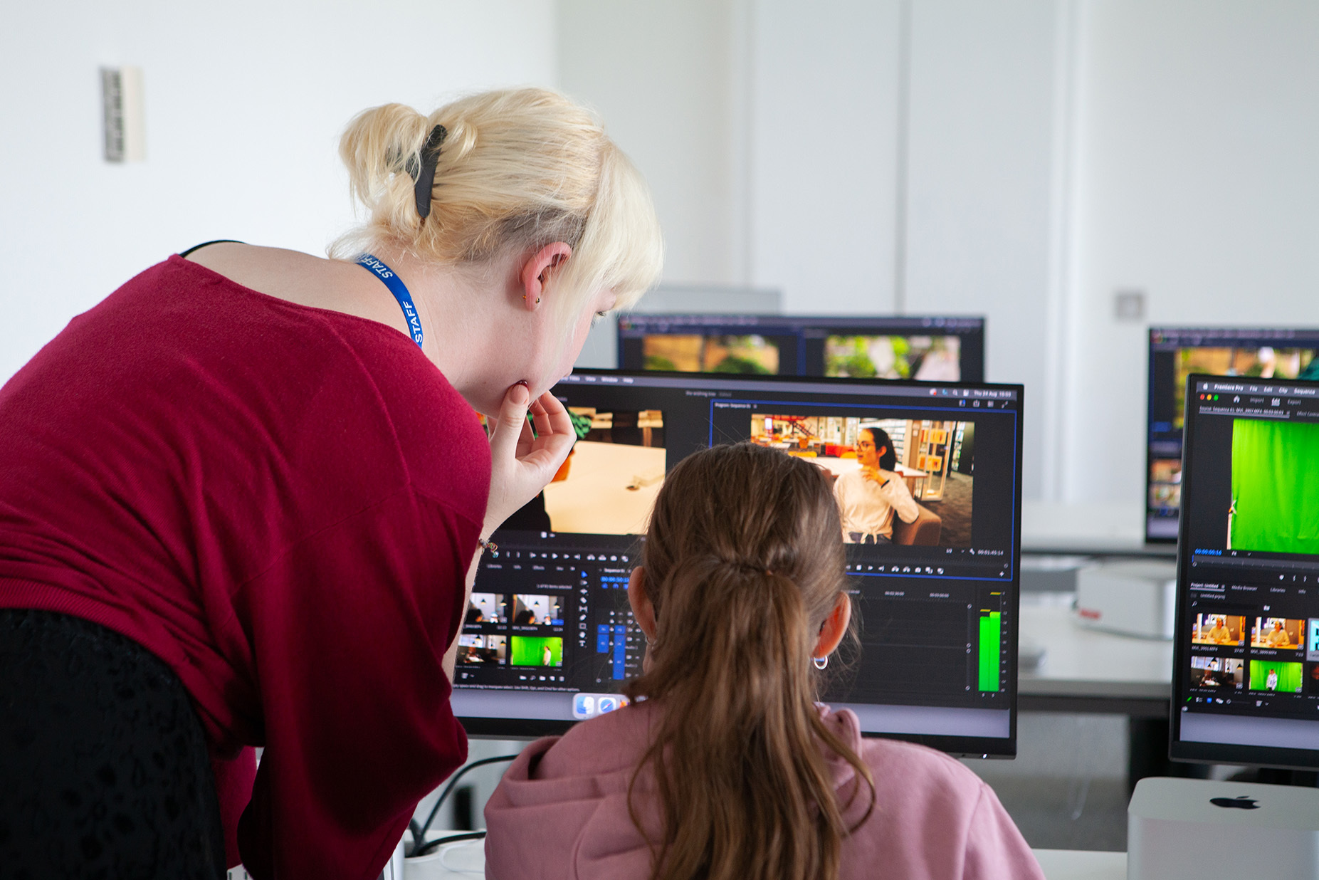 A teacher helps a student edit their film on a pc
