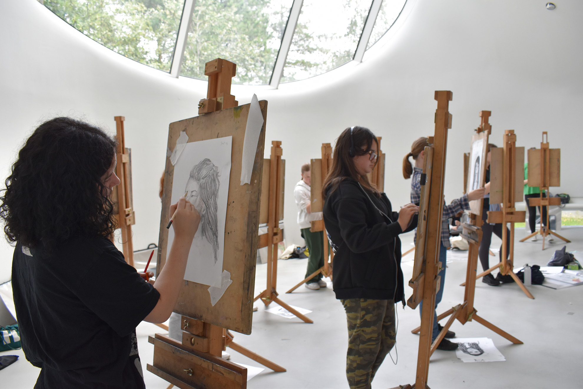 Students are drawing portraits on easels