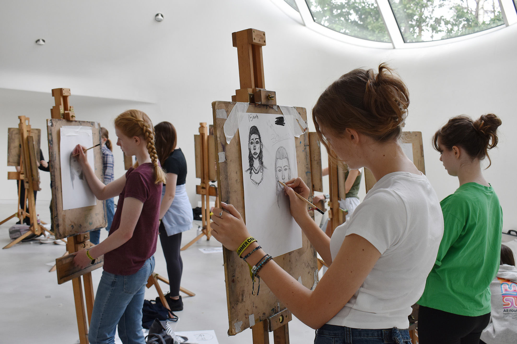 Students are drawing portraits on easels