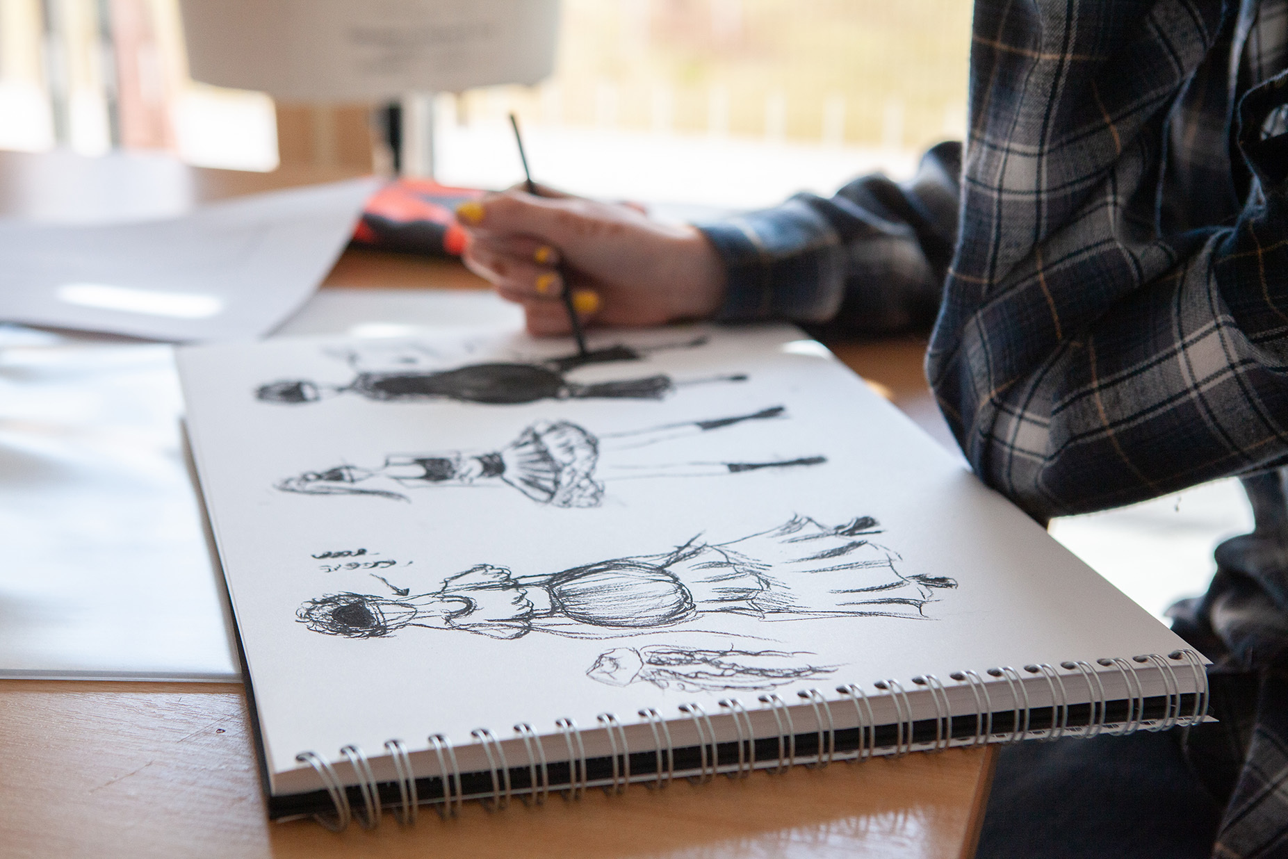 A student is sketching fashion illustrations