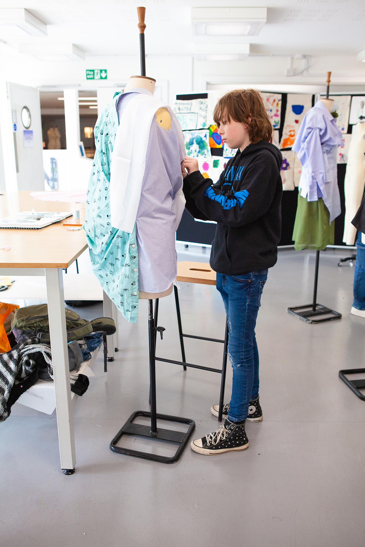 A student is working on a garment pinned to a mannequin