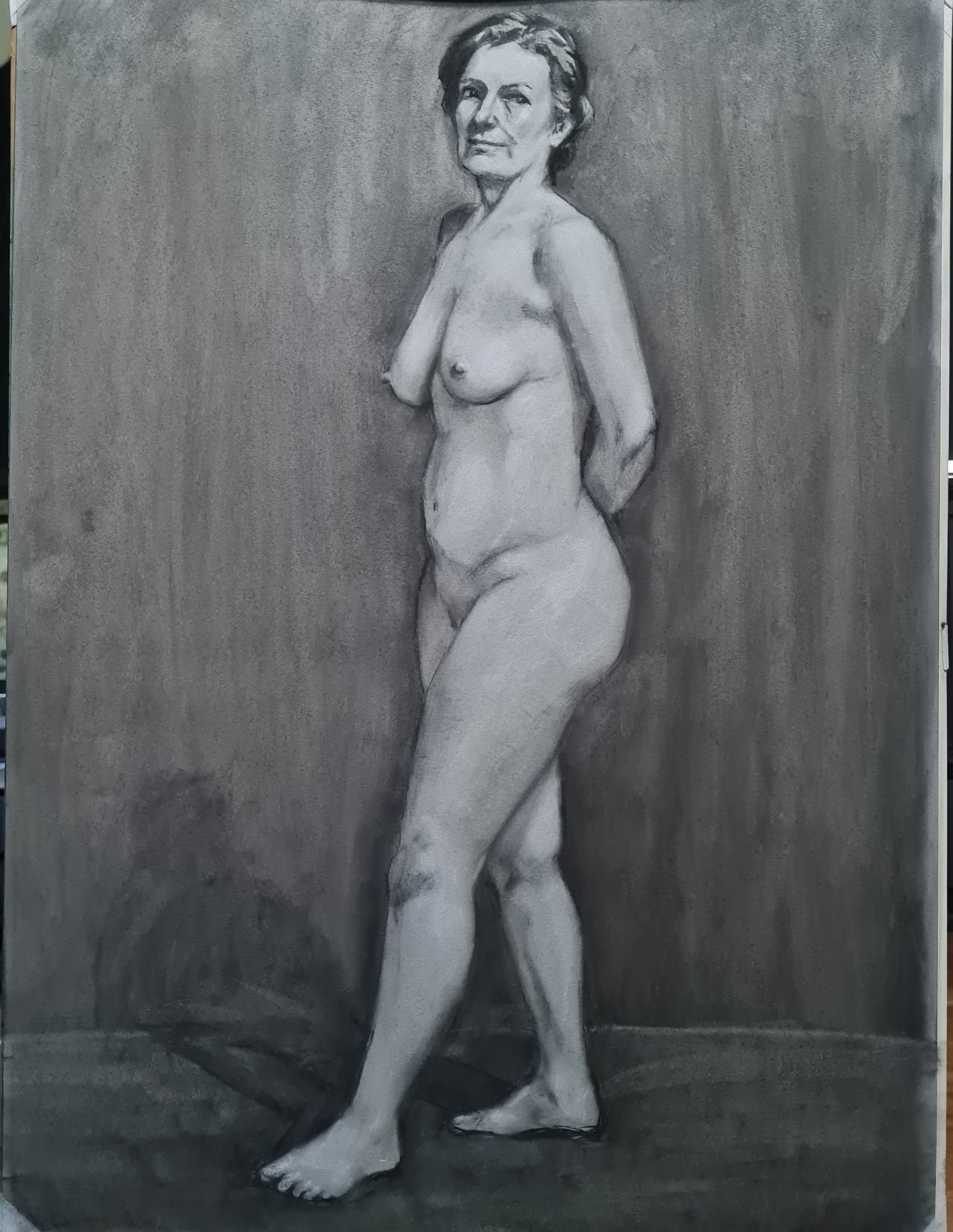 Painted nude figure study with pink flesh tones against muted grey-green background, standing pose with hand on hip.