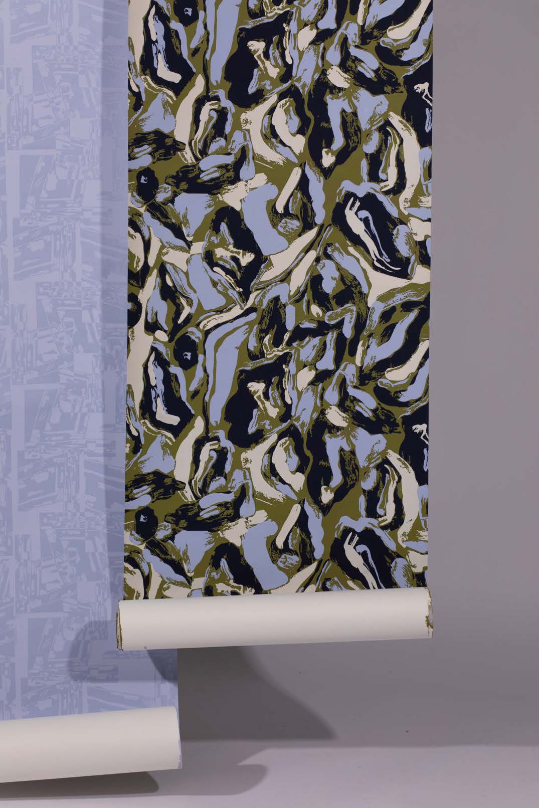 A patterned wallpaper roll featuring abstract shapes in green, navy blue, cream, and light blue tones. The roll is partially unwound, with the top edge visible and a white core at the bottom.