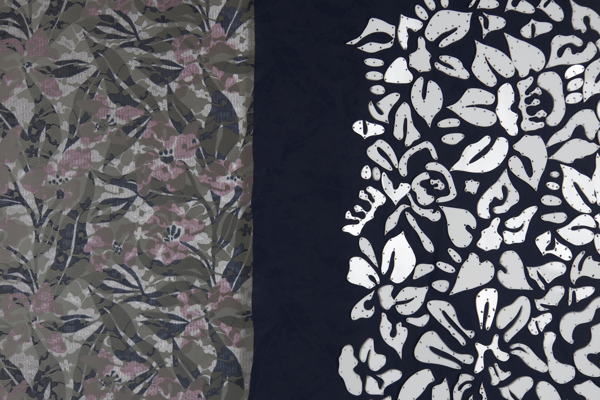A textile featuring two distinct patterns: on the left, a camouflage design with muted greens and pinks, and on the right, a navy background embellished with white floral motifs.