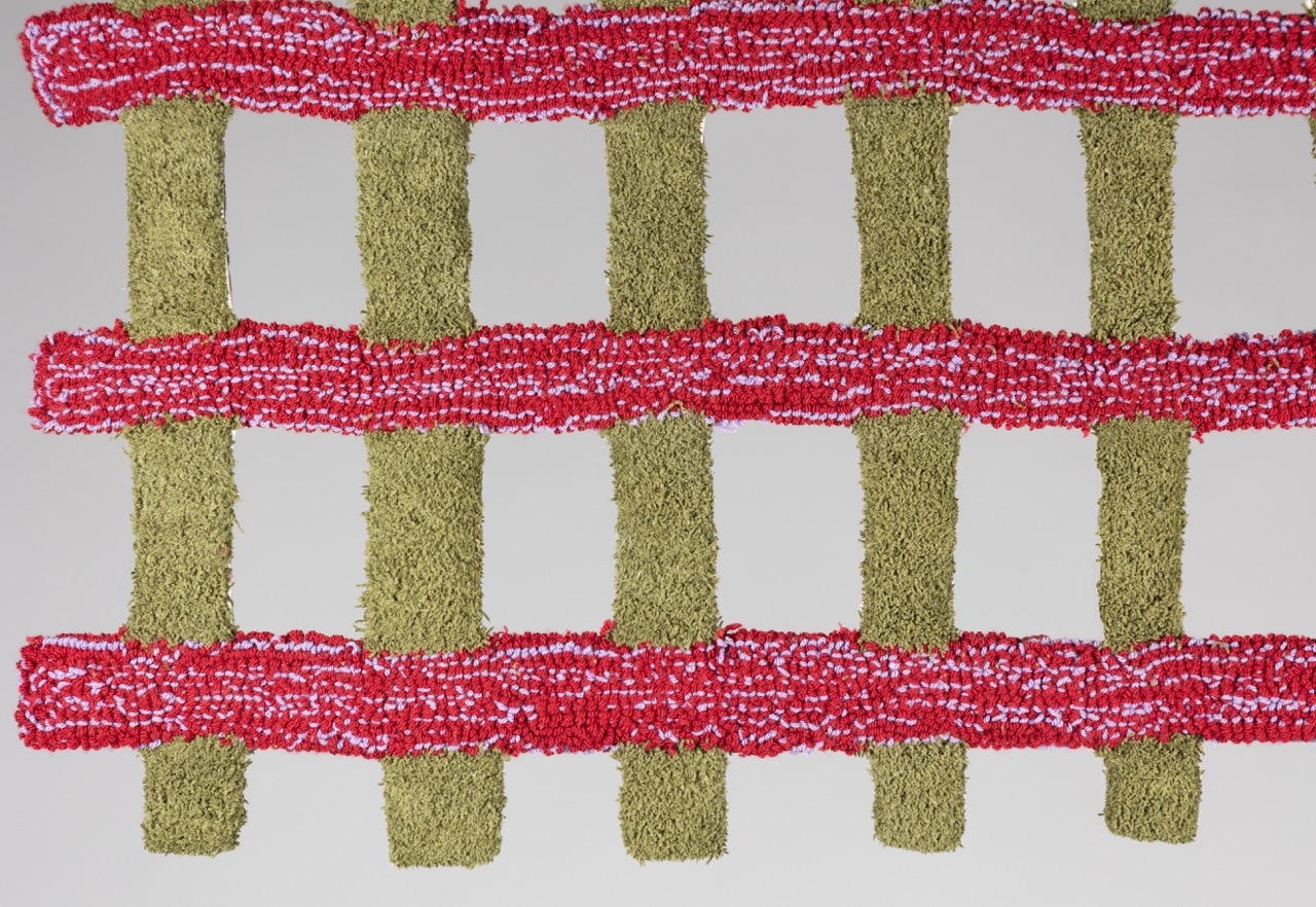An abstract textile arrangement featuring horizontal red and white striped strips interwoven with vertical green and beige textured strips, creating a grid-like pattern against a plain white background.
