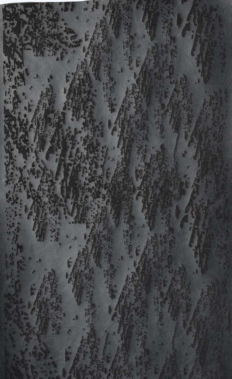 A textured abstract pattern featuring dark grey and black tones, with a series of diagonal lines and shapes resembling mountains or peaks, creating a layered appearance across the surface.
